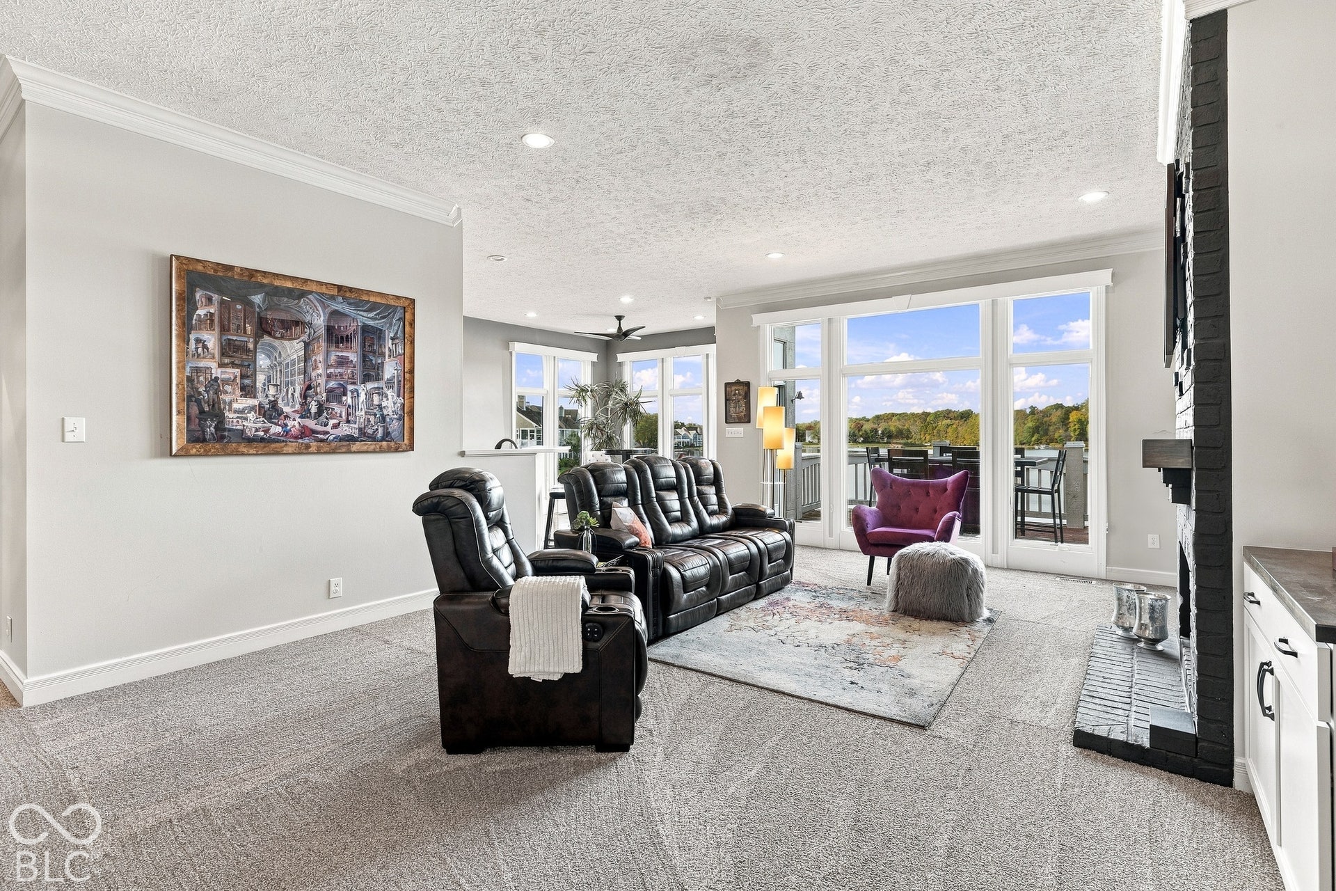 Living area featuring a floor-to-ceiling painted brick fireplace, recessed lighting, crown molding, and expansive windows with natural light