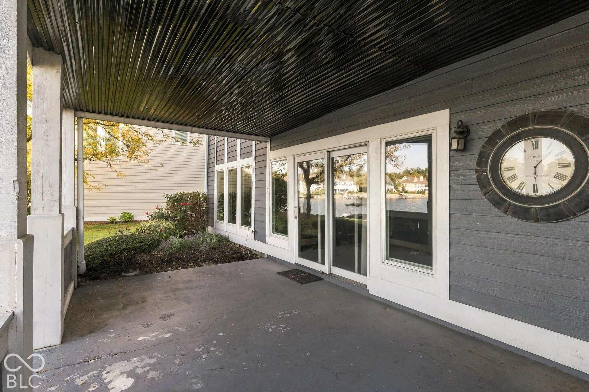 Covered patio featuring a corrugated metal ceiling, horizontal lap siding, and sliding glass doors