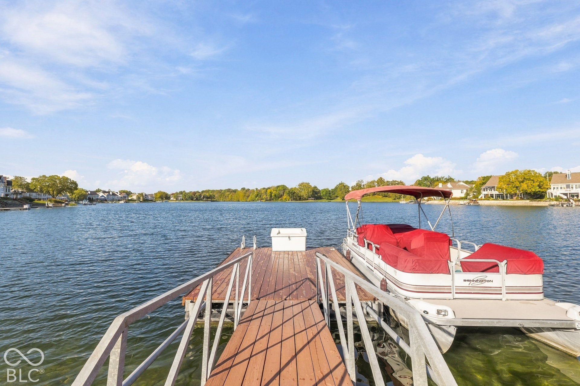 Private dock with wood-finish decking, metal railings, and storage box extending into the lake