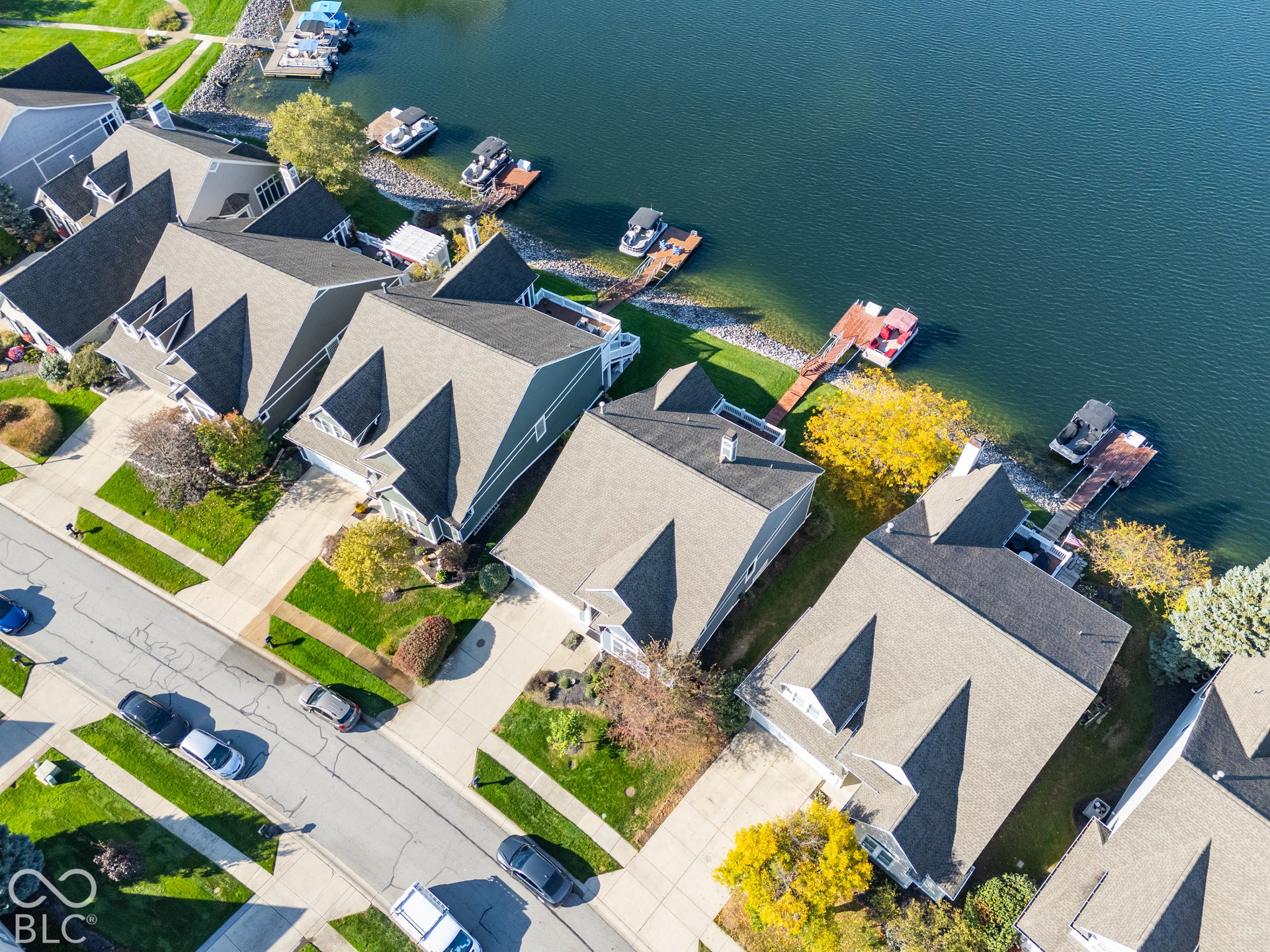 Aerial perspective of lakeside residences featuring private docks, manicured lawn areas, and shingle-style rooflines