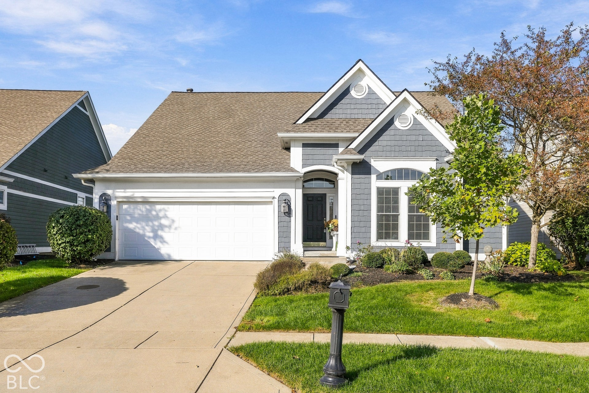 Exterior facade featuring grey shake siding, white trim accents, arched entryway, concrete driveway, and attached two-car garage