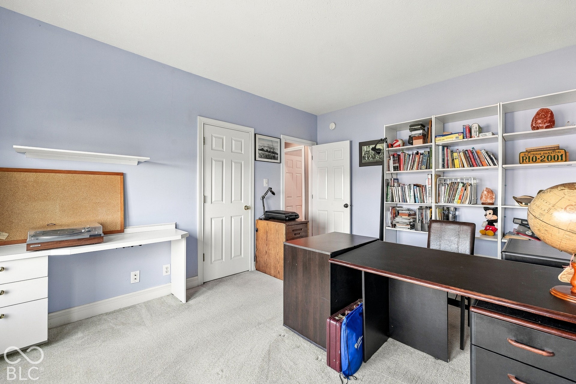 Built-in white shelving unit, wall-mounted desk with integrated storage drawers, and two interior six-panel doors