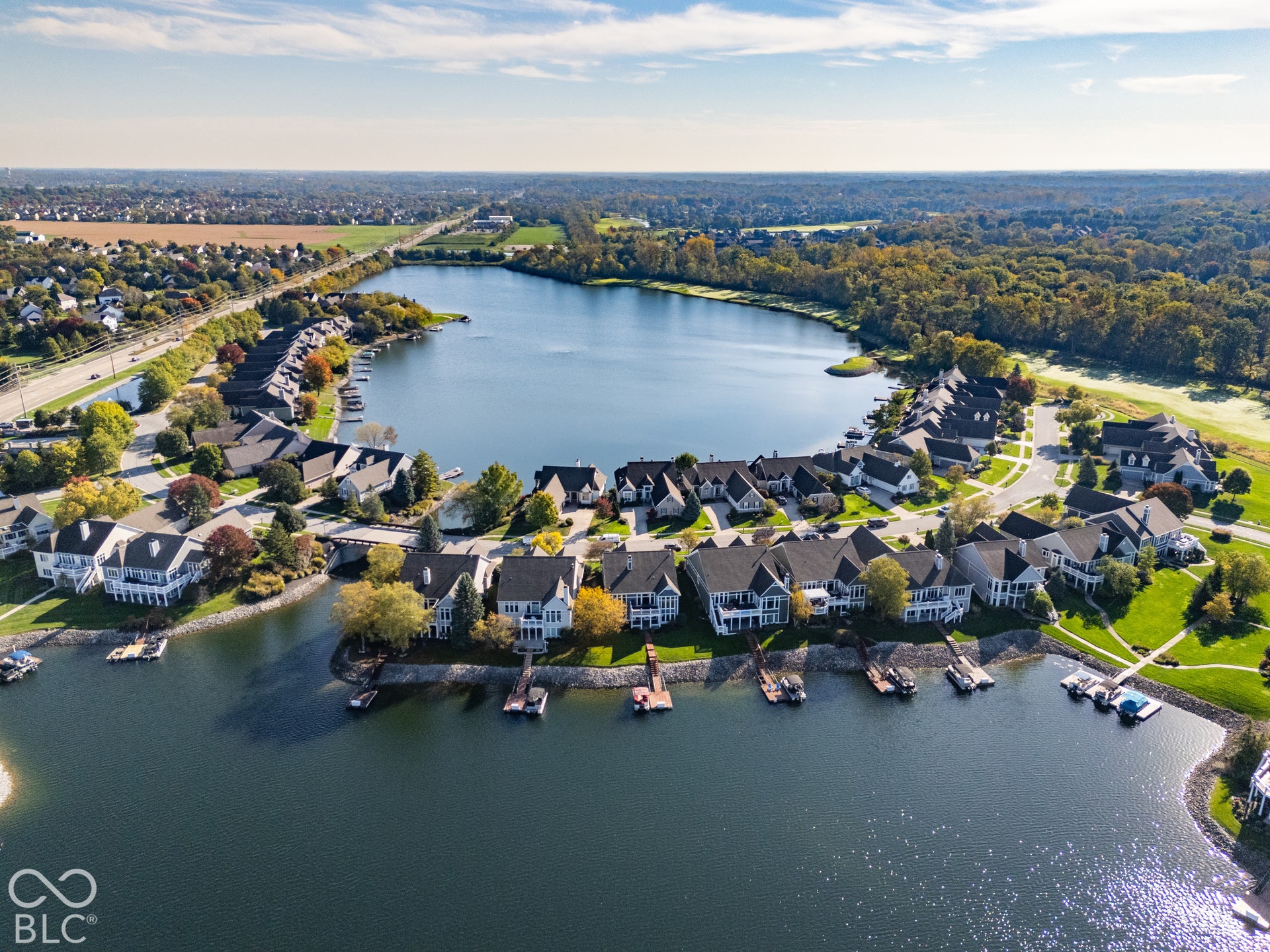 Aerial perspective of lakeside residential community featuring private boat docks, waterfront access, shoreline rock revetment, and mature tree-lined surroundings