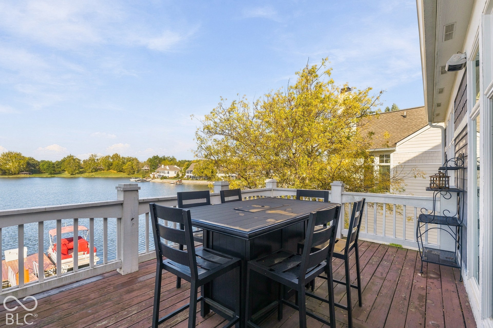 Elevated wooden deck featuring white railing and direct water access with a private dock