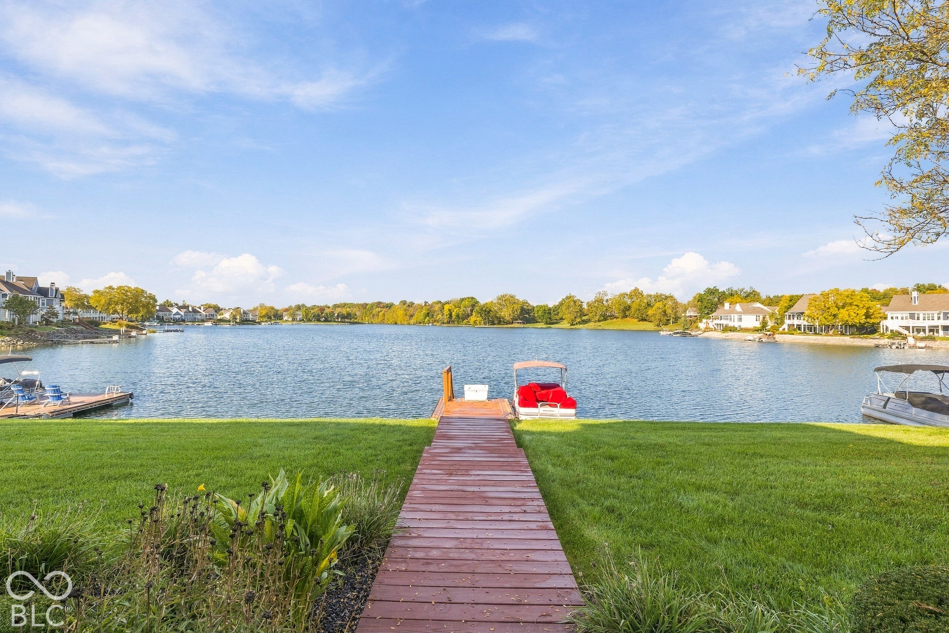 Waterfront property featuring a manicured lawn and a wooden pier