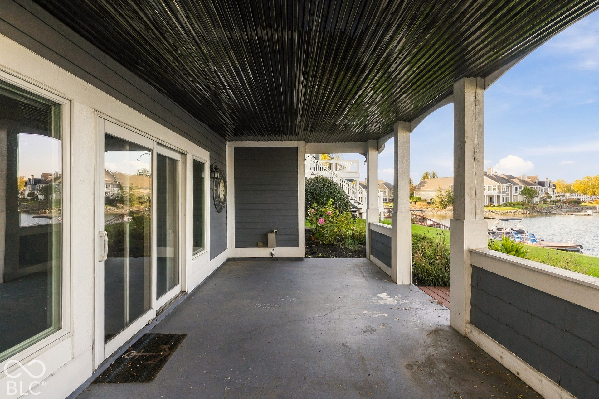 Covered patio featuring a corrugated metal ceiling, horizontal lap siding, and white structural support columns