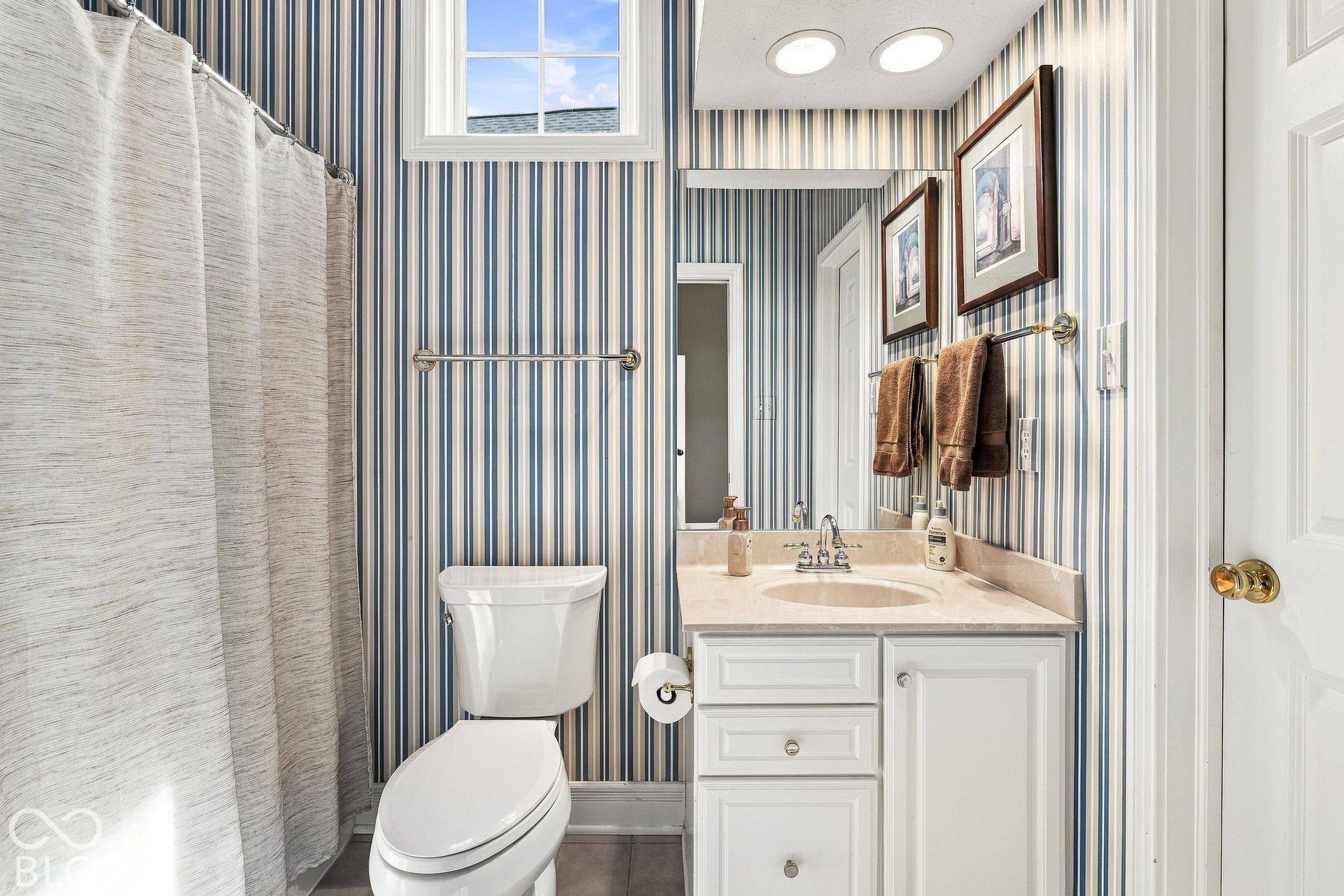 Bathroom featuring a white vanity cabinet with an integrated sink and light-toned countertop, vertical-striped wallpaper, transom window, and recessed ceiling lighting
