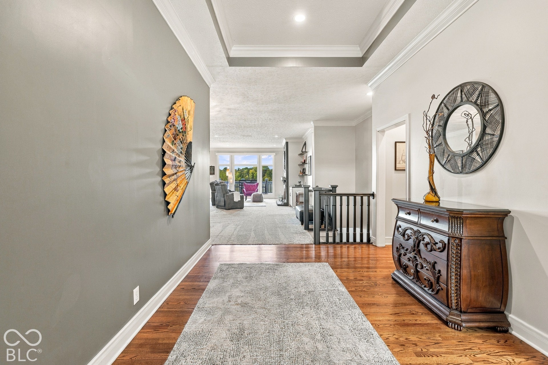 Entryway featuring wood-finish flooring, tray ceiling, and decorative railing