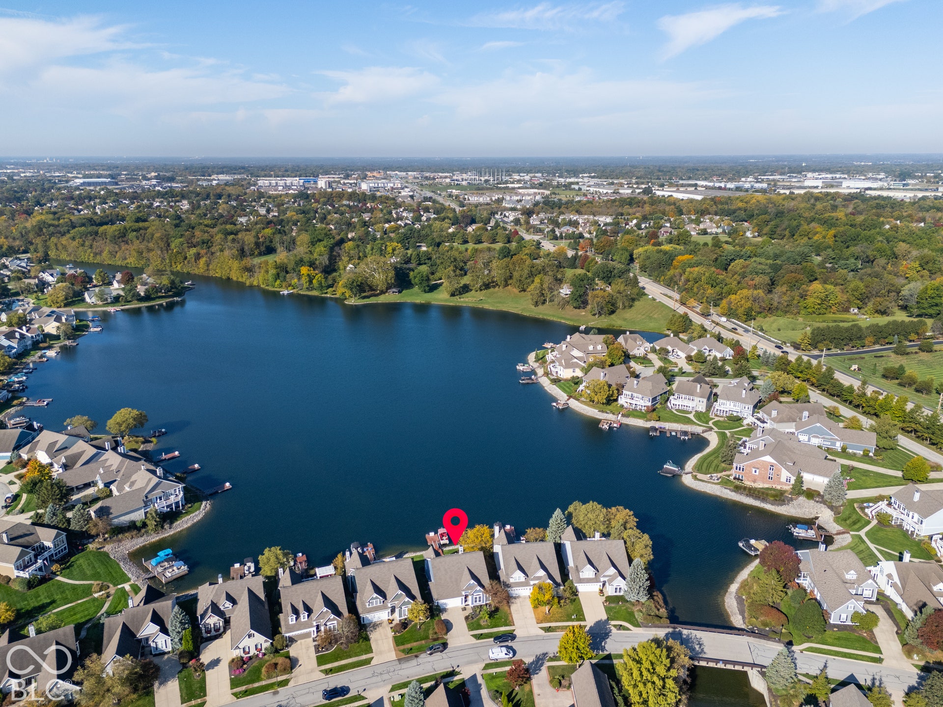 Aerial perspective of a waterfront residential property featuring direct water frontage, a private boat slip, and multi-level roof architecture