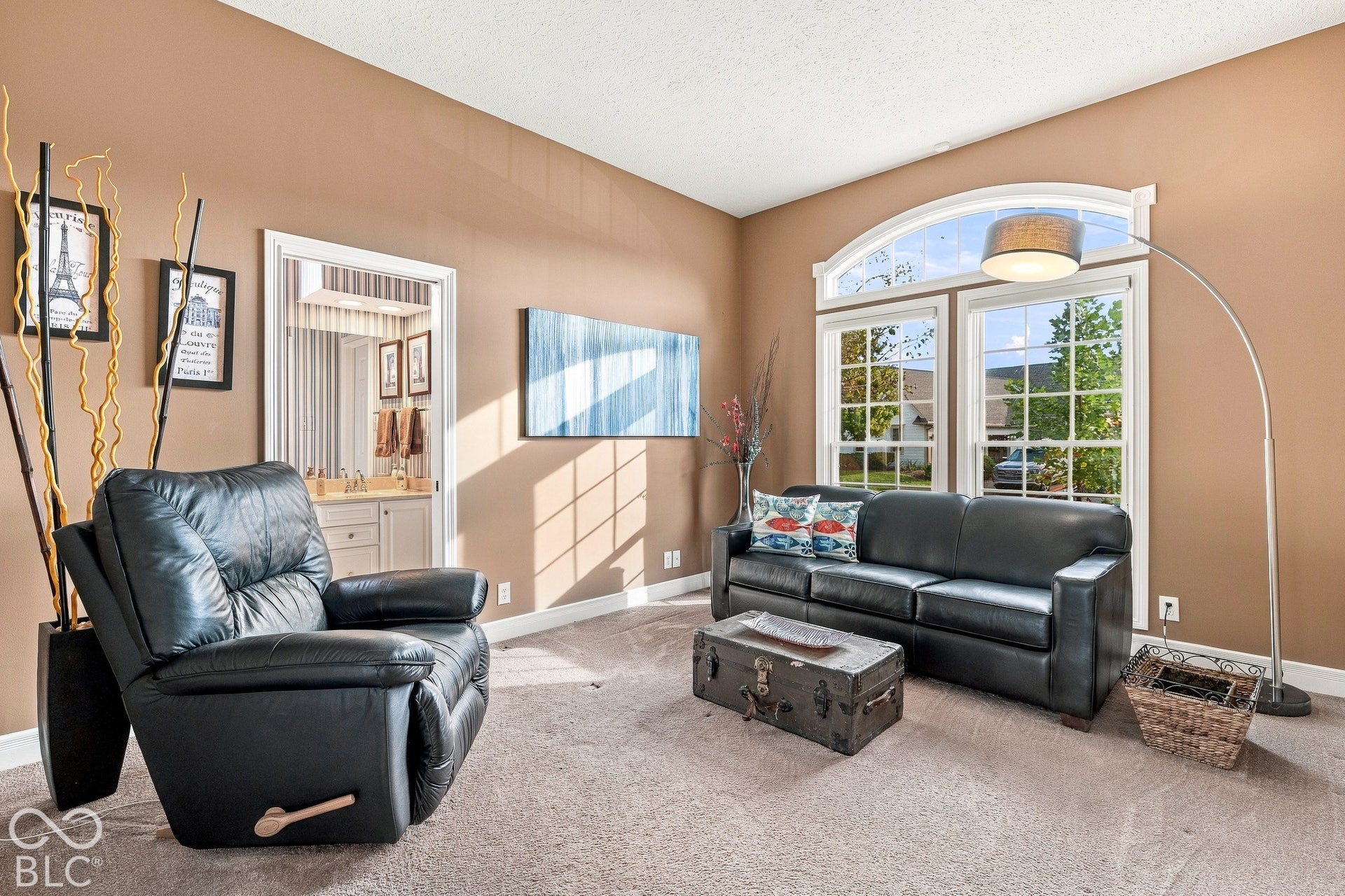 High-ceiling living area featuring large windows with an arched transom and wall-to-wall carpeting