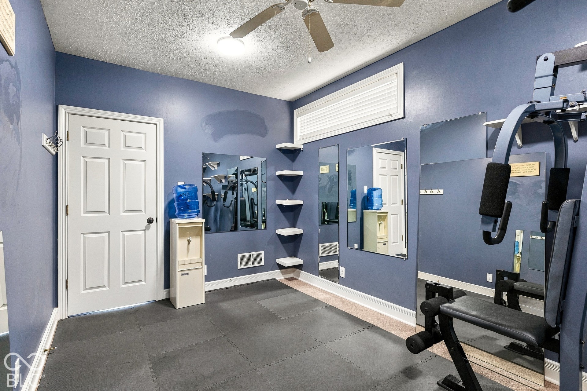 Room featuring wall-mounted mirrors, built-in floating shelves, a horizontal transom window, and a ceiling fan