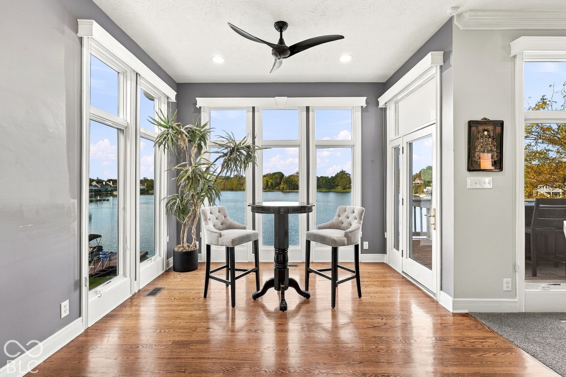 Sunroom featuring wood-finish flooring, floor-to-ceiling windows, a ceiling fan, and a glass-paneled exterior door