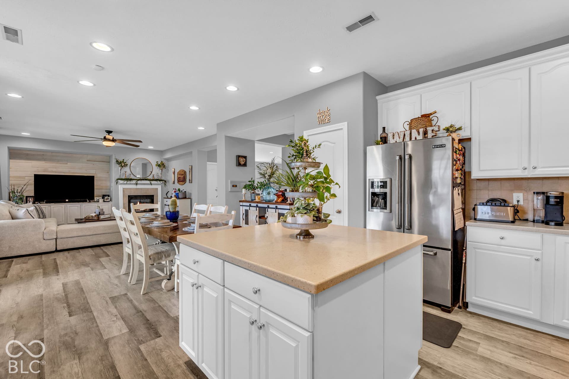Well-appointed kitchen featuring white cabinetry, stainless steel refrigerator, and a kitchen island with a solid surface countertop