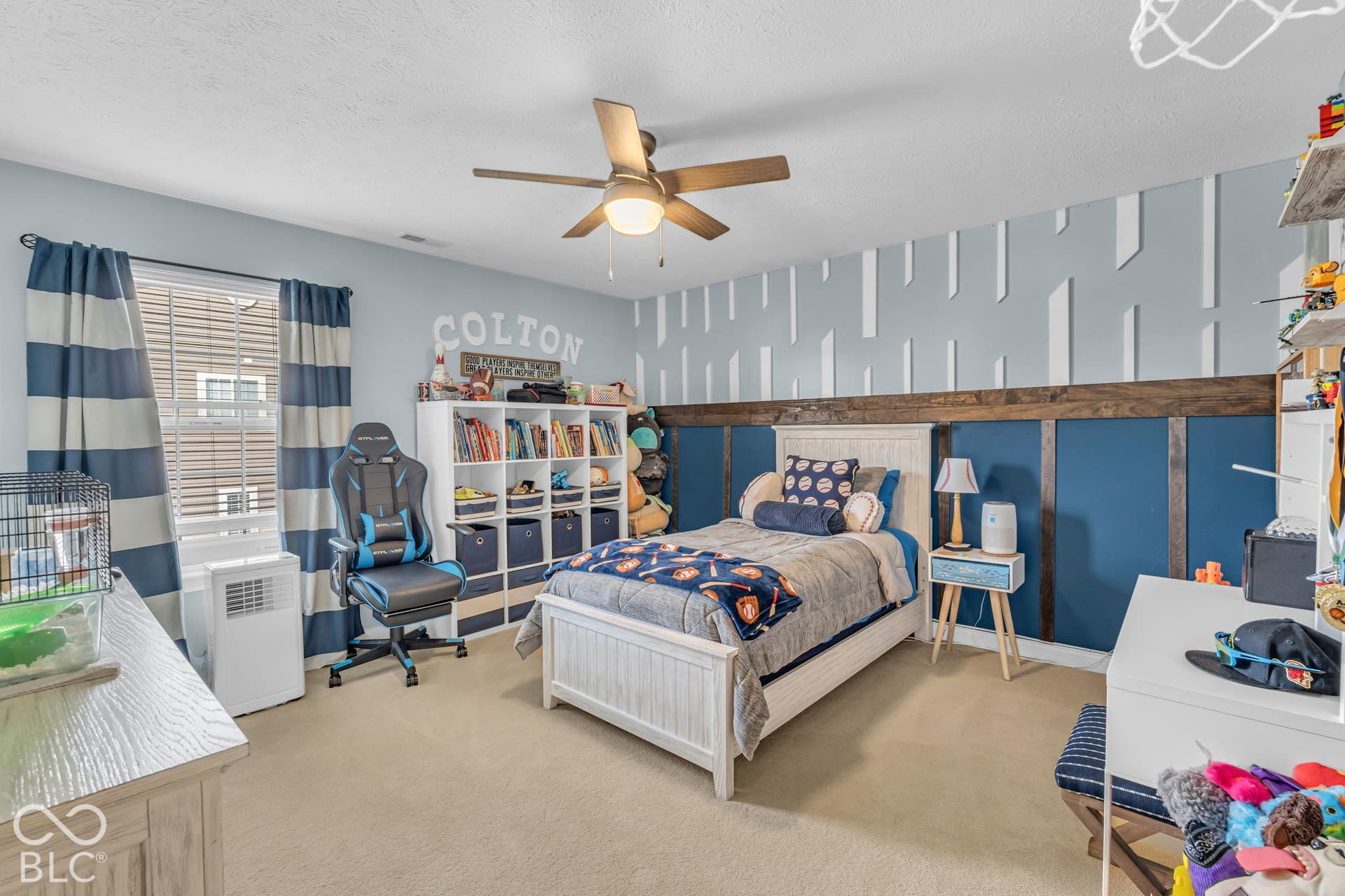 Carpeted bedroom featuring a ceiling fan, a window with blinds, and a built-in bookshelf