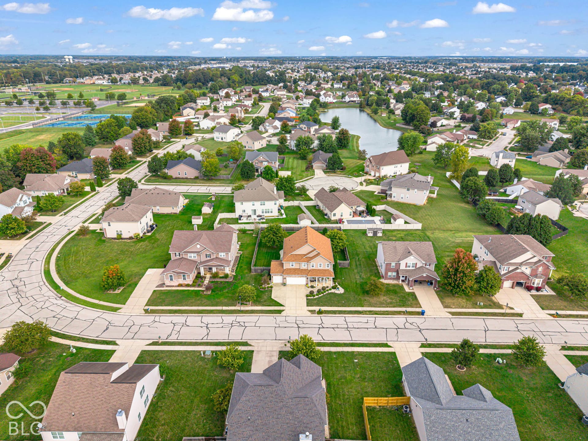 Community setting featuring residential properties, mature trees, and a central pond
