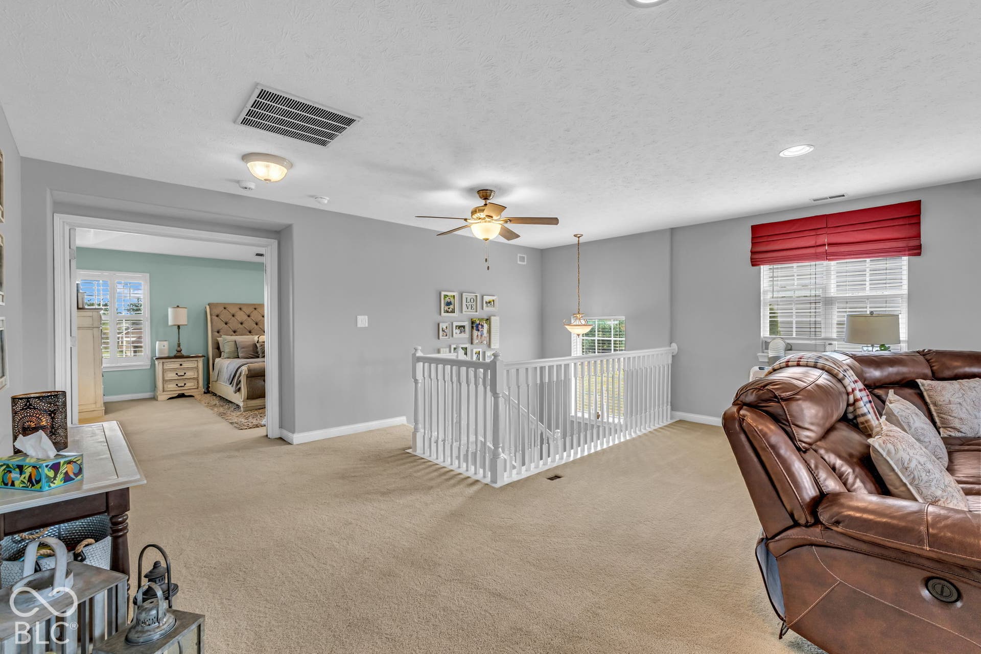 Carpeted loft area with recessed lighting, ceiling fan, and white railing overlooking the lower level