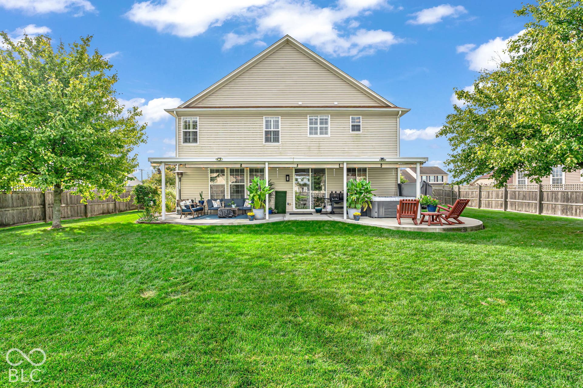 Expansive rear lawn, covered patio, privacy fencing, additional patio space, and a built-in spa