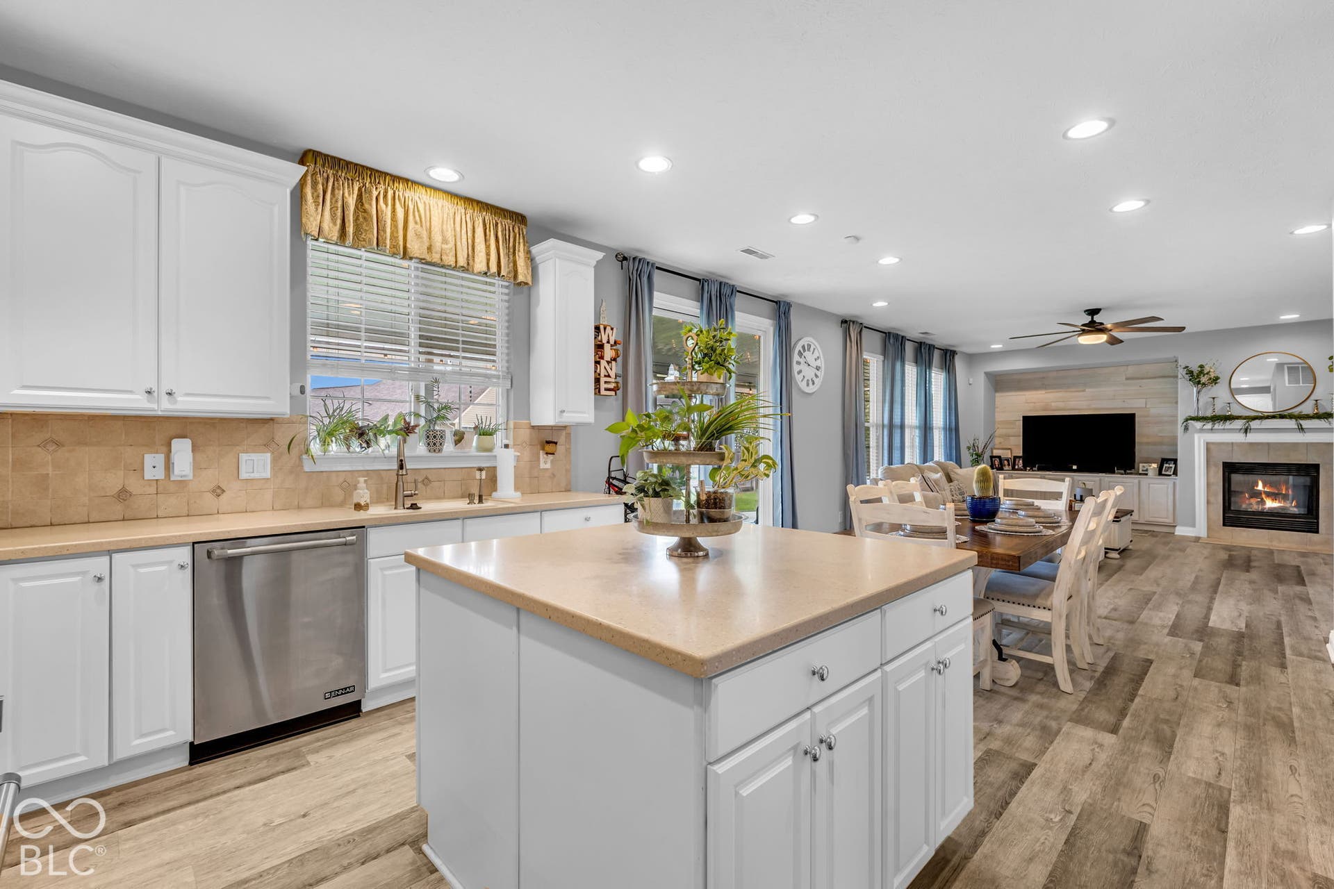 White shaker-style cabinetry with a kitchen island, stainless steel dishwasher, and wood-finish flooring