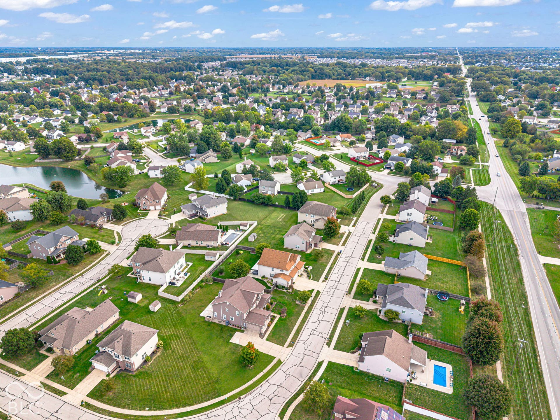 Residential neighborhood with mature trees, a tranquil pond, and well-maintained properties