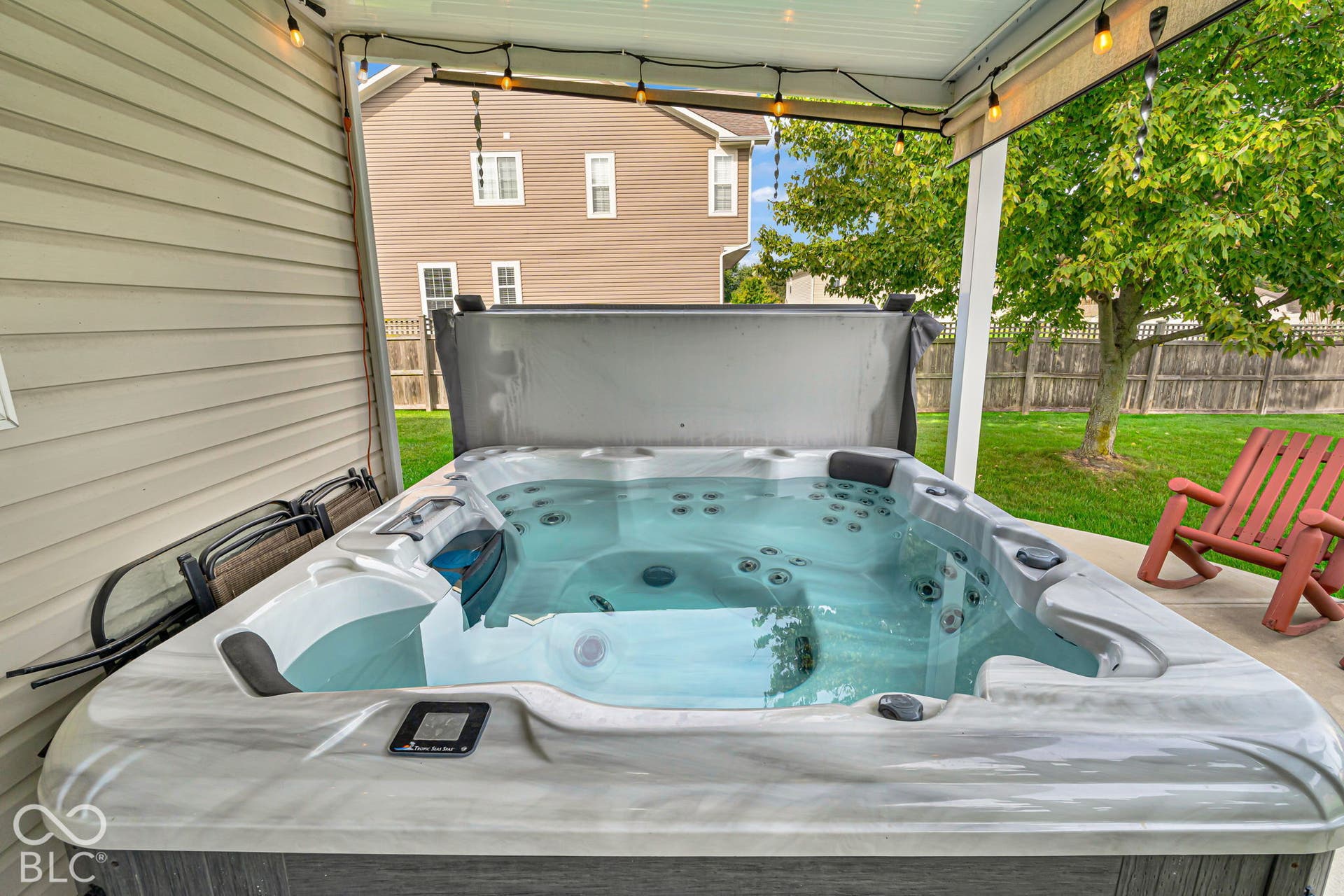 Luxurious hot tub featuring dual loungers, multiple therapeutic jets, and integrated lighting, positioned under a covered pavilion