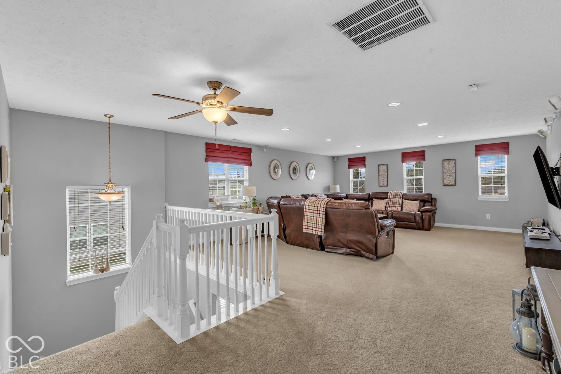 Spacious loft area featuring carpeting and multiple windows