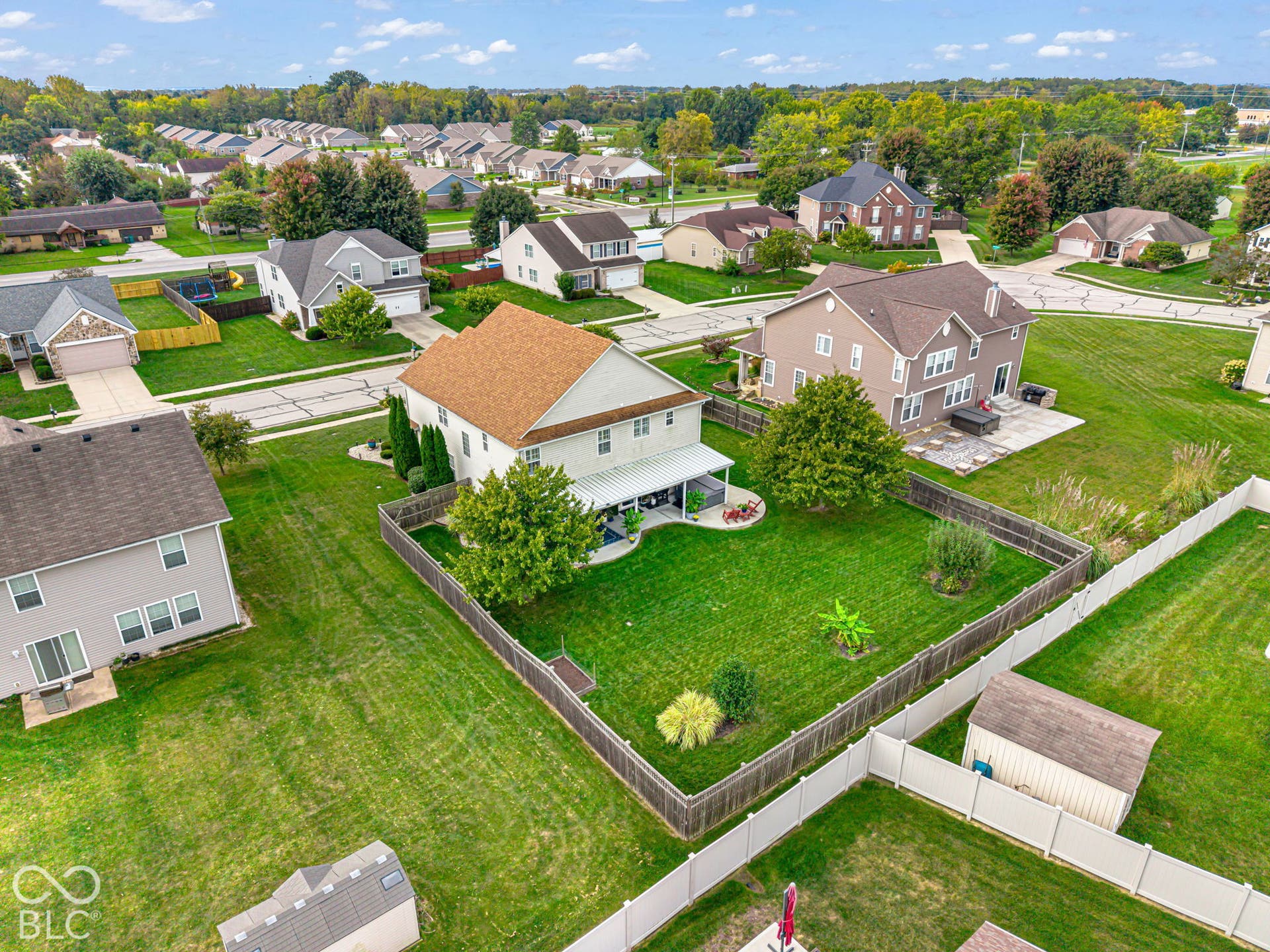Expansive fenced backyard with a patio and mature trees