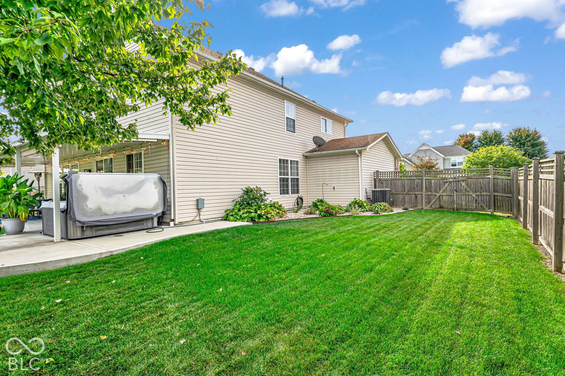 Expansive backyard featuring a manicured lawn, established privacy fencing, and a concrete patio with a covered pergola
