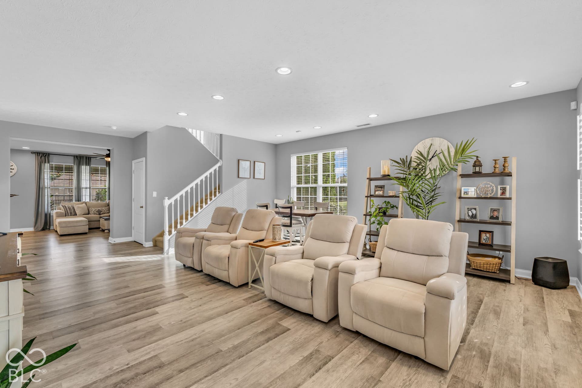 Recessed lighting, wood-finish flooring, white spindle staircase, and window with exterior greenery