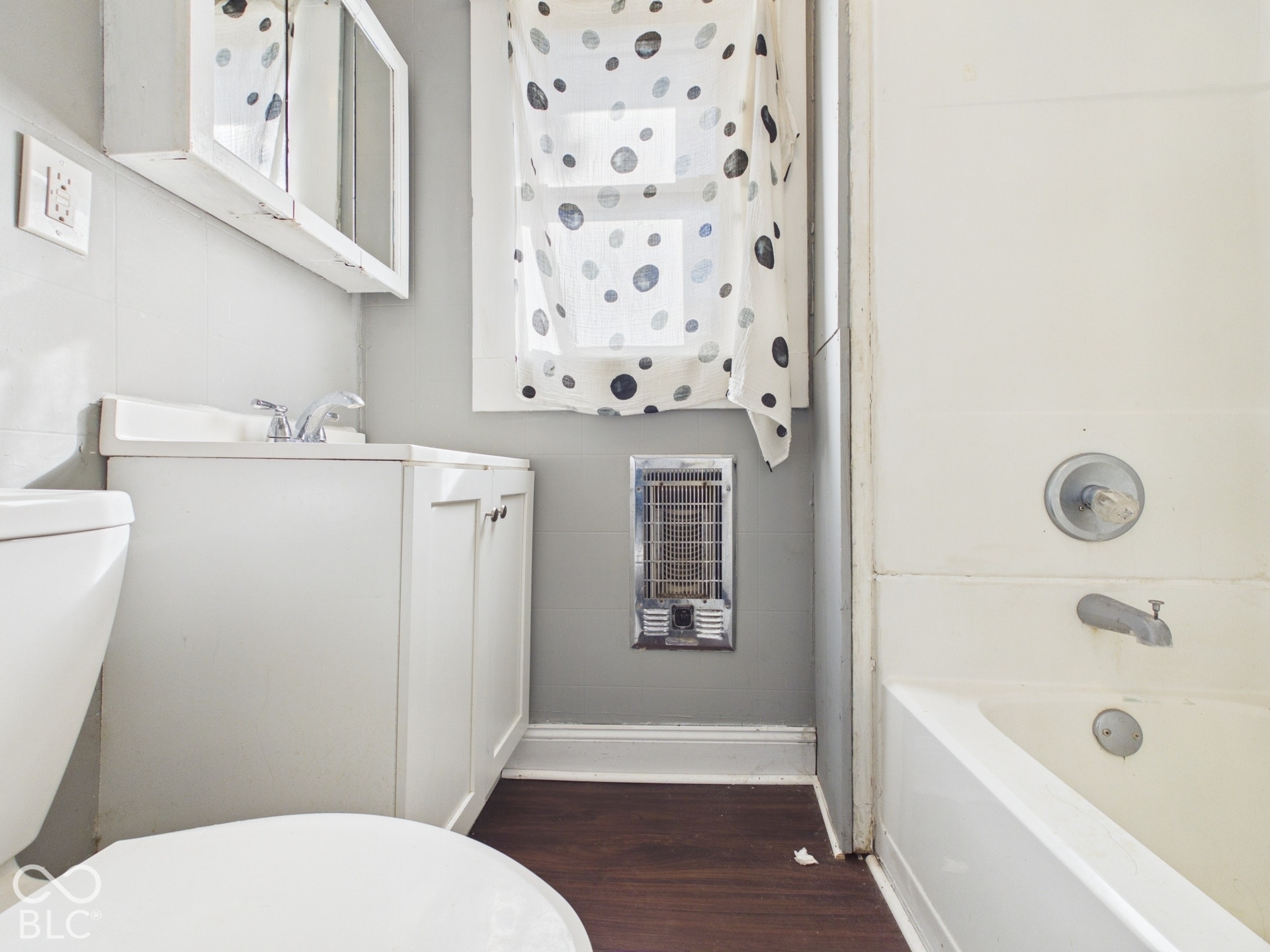 White vanity with chrome faucet and medicine cabinet, adjacent to a white bathtub with chrome fixtures
