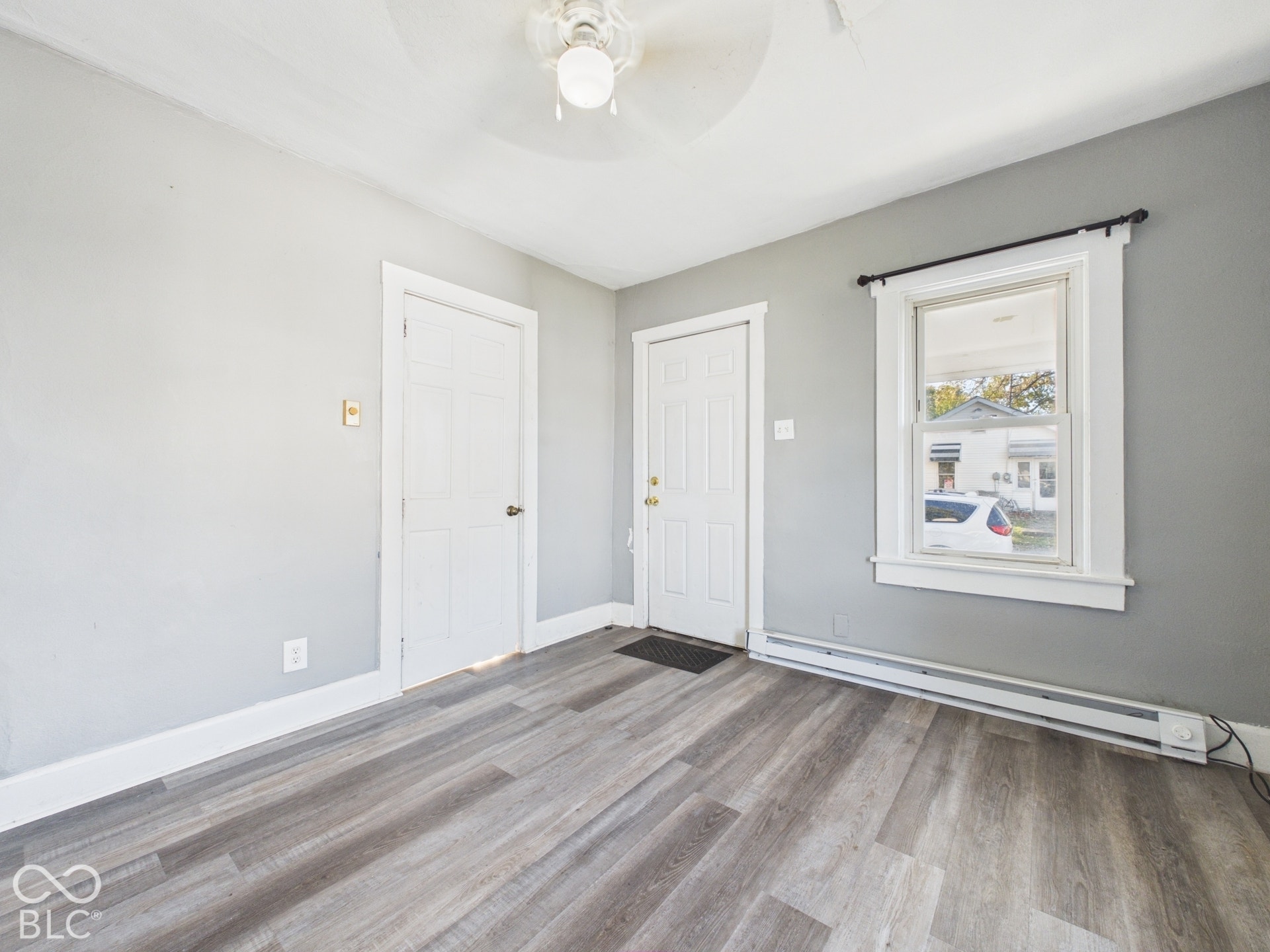 Wood-finish flooring with a neutral paint palette, white trim, and a ceiling fan