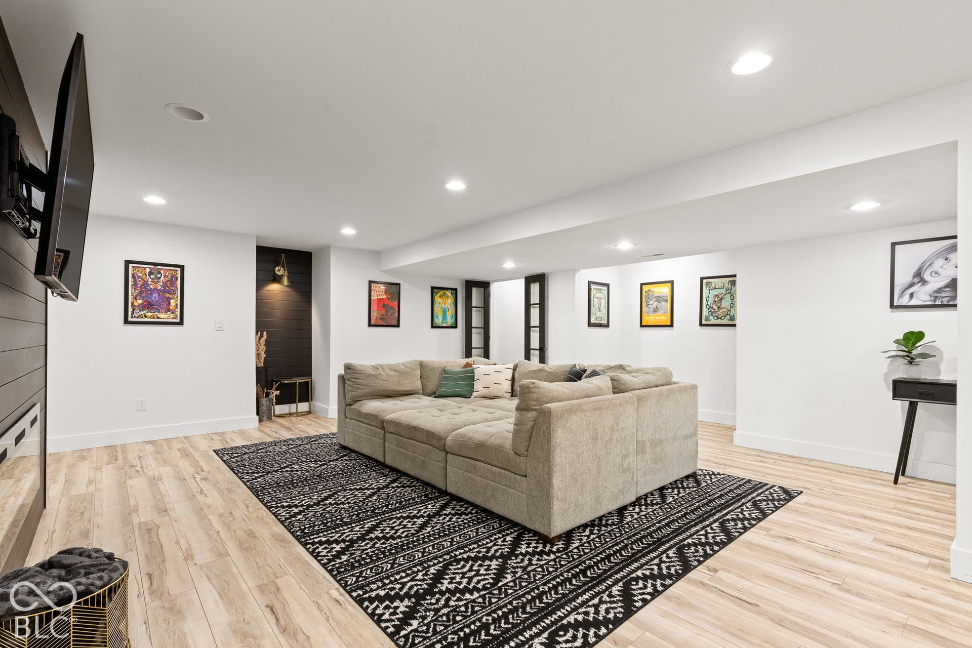 Recessed ceiling lighting, LVP flooring, accent wall with sconce lighting, white walls, and a built-in entertainment wall