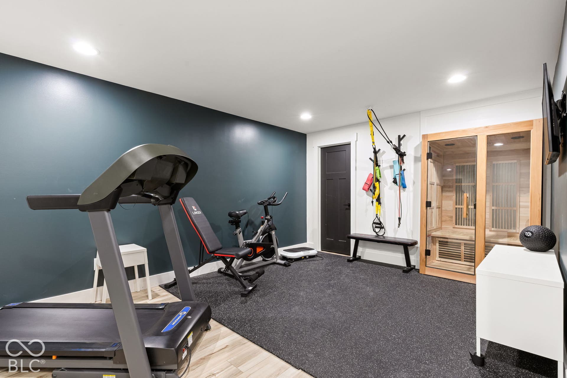 Built-in sauna with a glass door and wood-panel interior, recessed lighting, accent wall, and rubber flooring