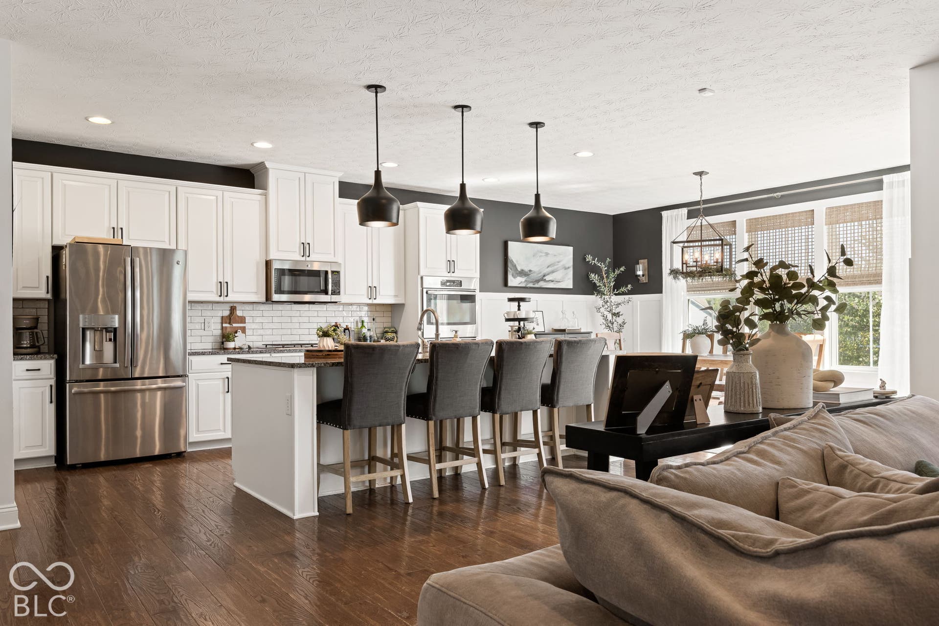Gourmet kitchen with stainless steel appliances, white cabinetry, a center island with seating, and wood-finish flooring