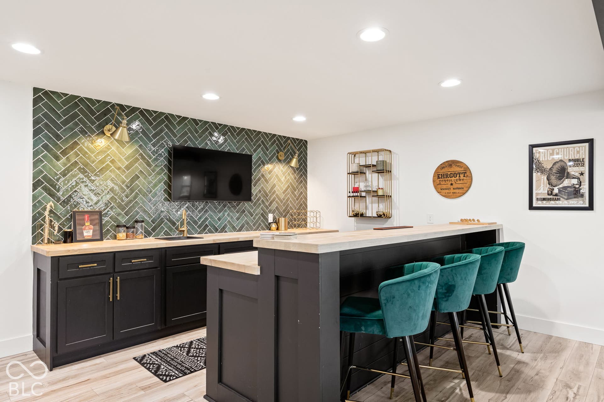 Herringbone tile accent wall, built-in cabinetry with gold-tone hardware, wood-finish countertops, undermount sink, and recessed lighting