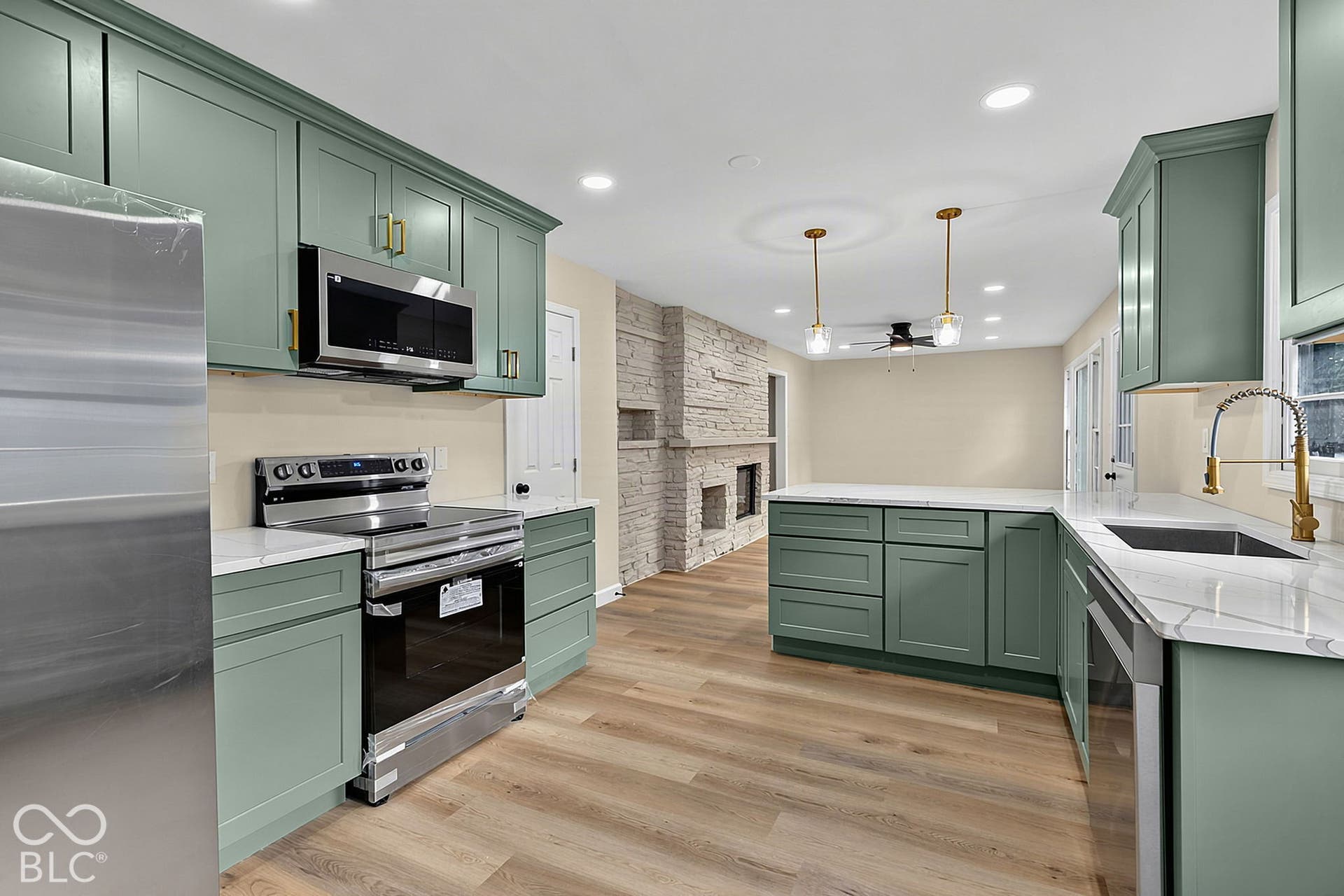 Contemporary kitchen featuring green cabinetry, stainless steel appliances, light-toned wood-finish flooring, white countertops, and recessed lighting
