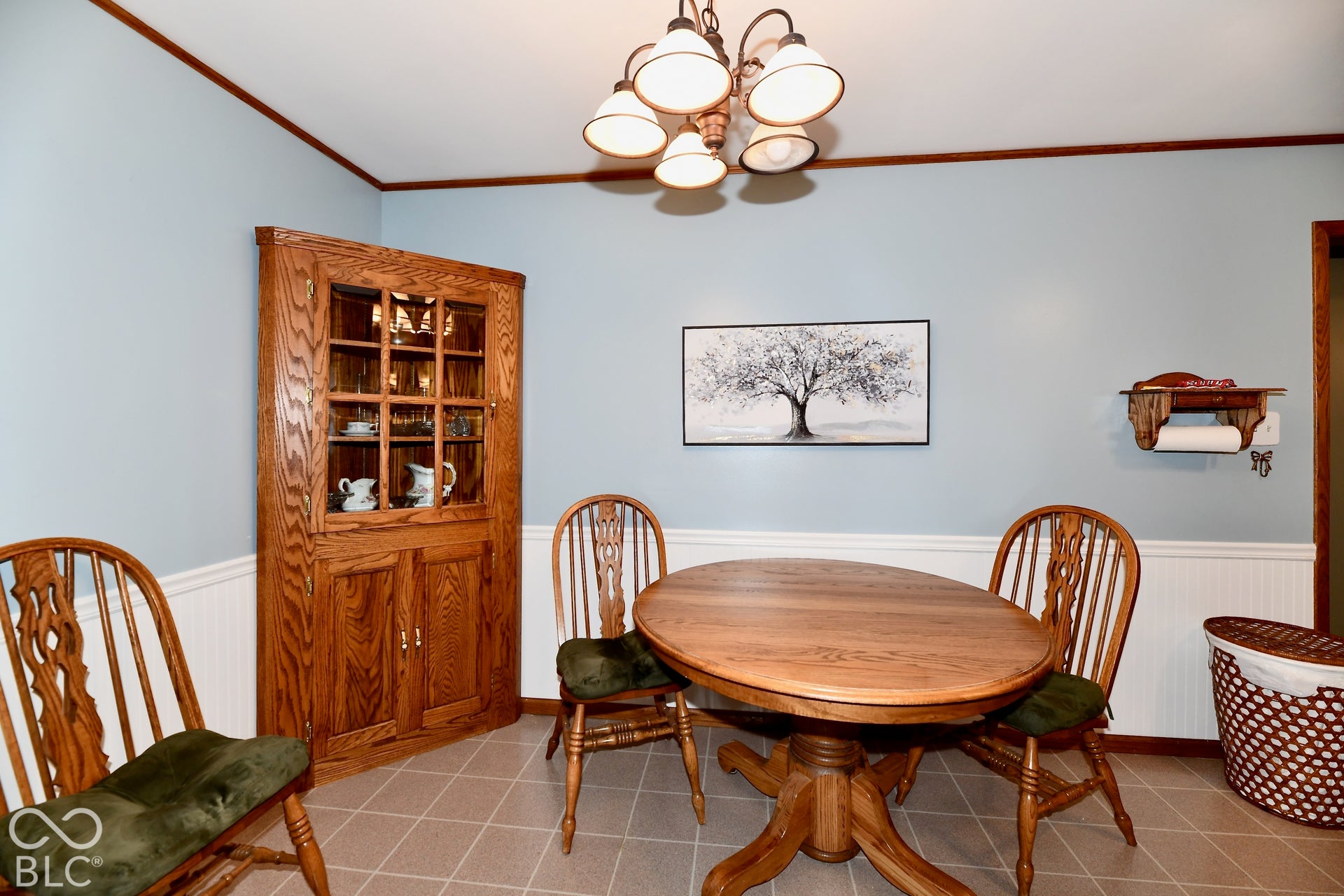 Custom corner cabinet with glass-front upper cabinetry, wainscoting and vinyl flooring
