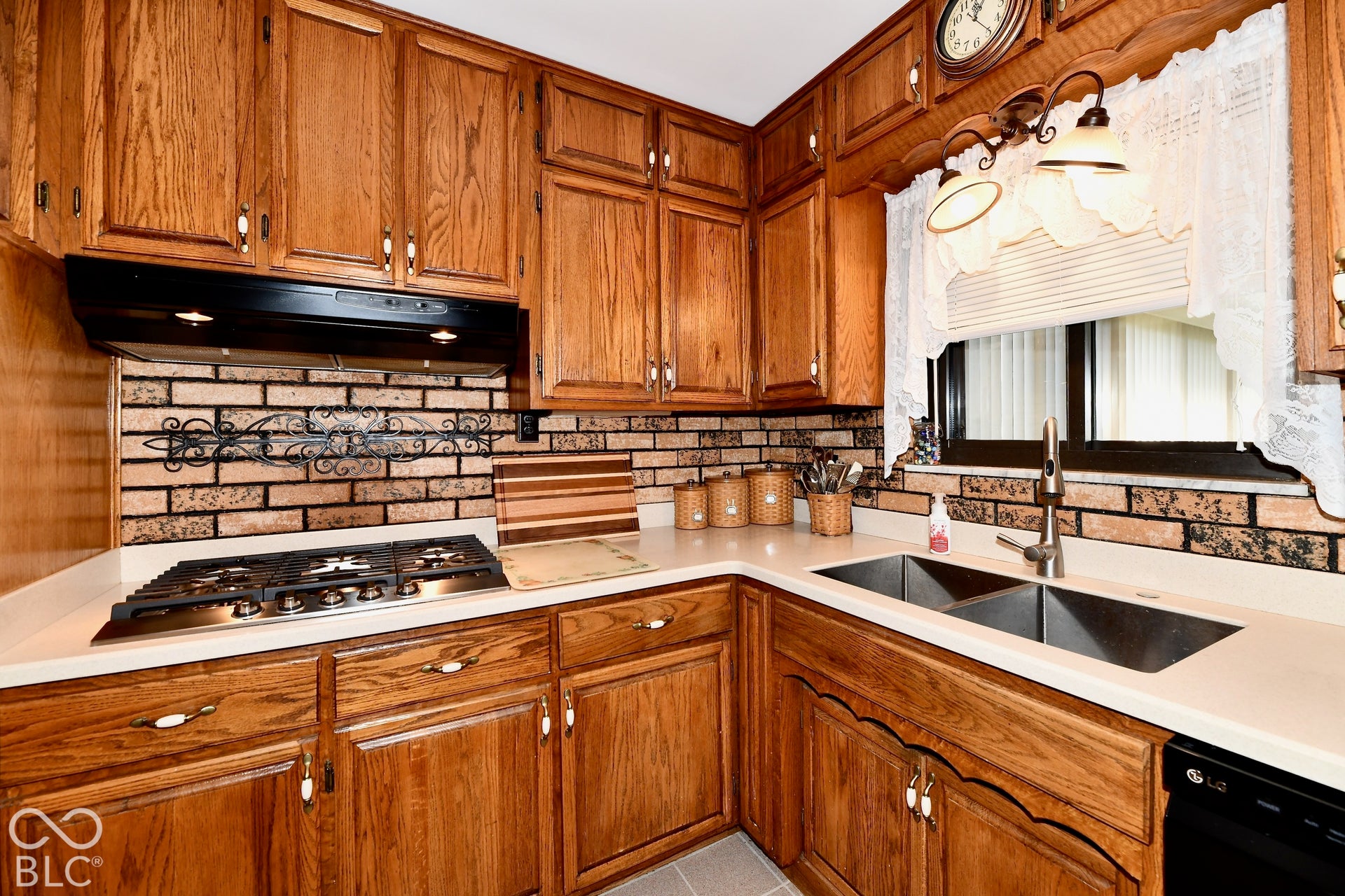 Warm wood cabinetry throughout this kitchen features stainless steel appliances, including a gas cooktop and dual undermount sinks