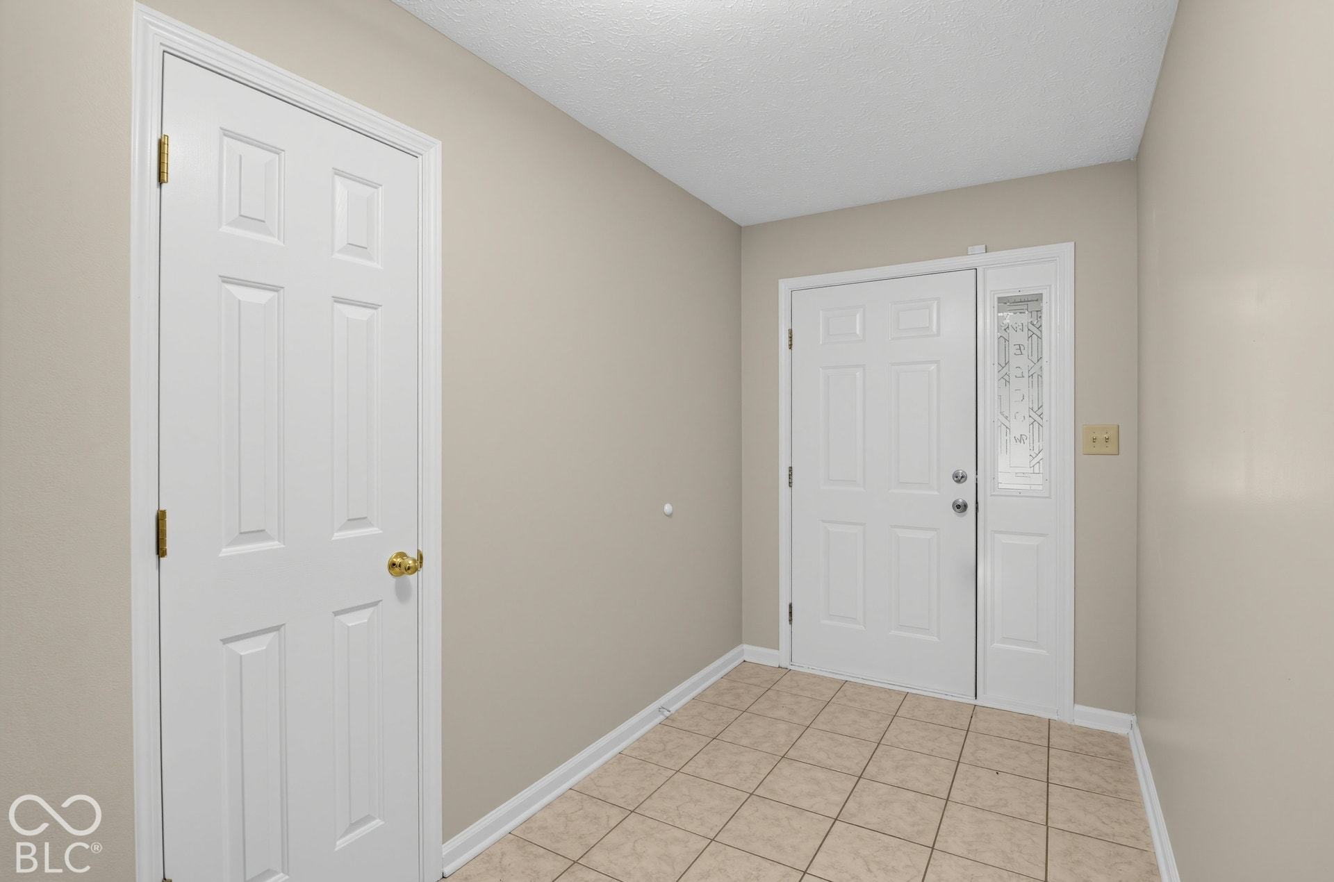 Entryway featuring ceramic tile flooring, a six-panel exterior door with a decorative glass sidelight, and a matching six-panel interior door