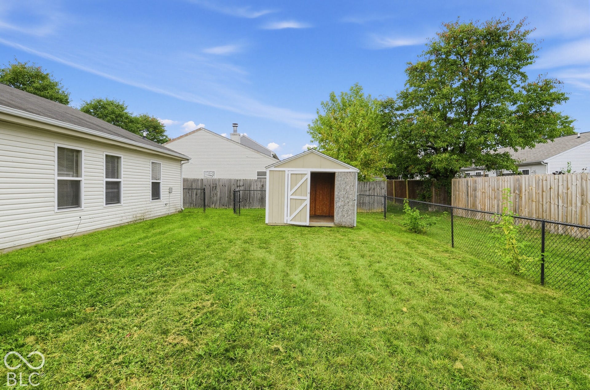Backyard featuring a grass lawn, detached storage shed, and perimeter chain-link fencing