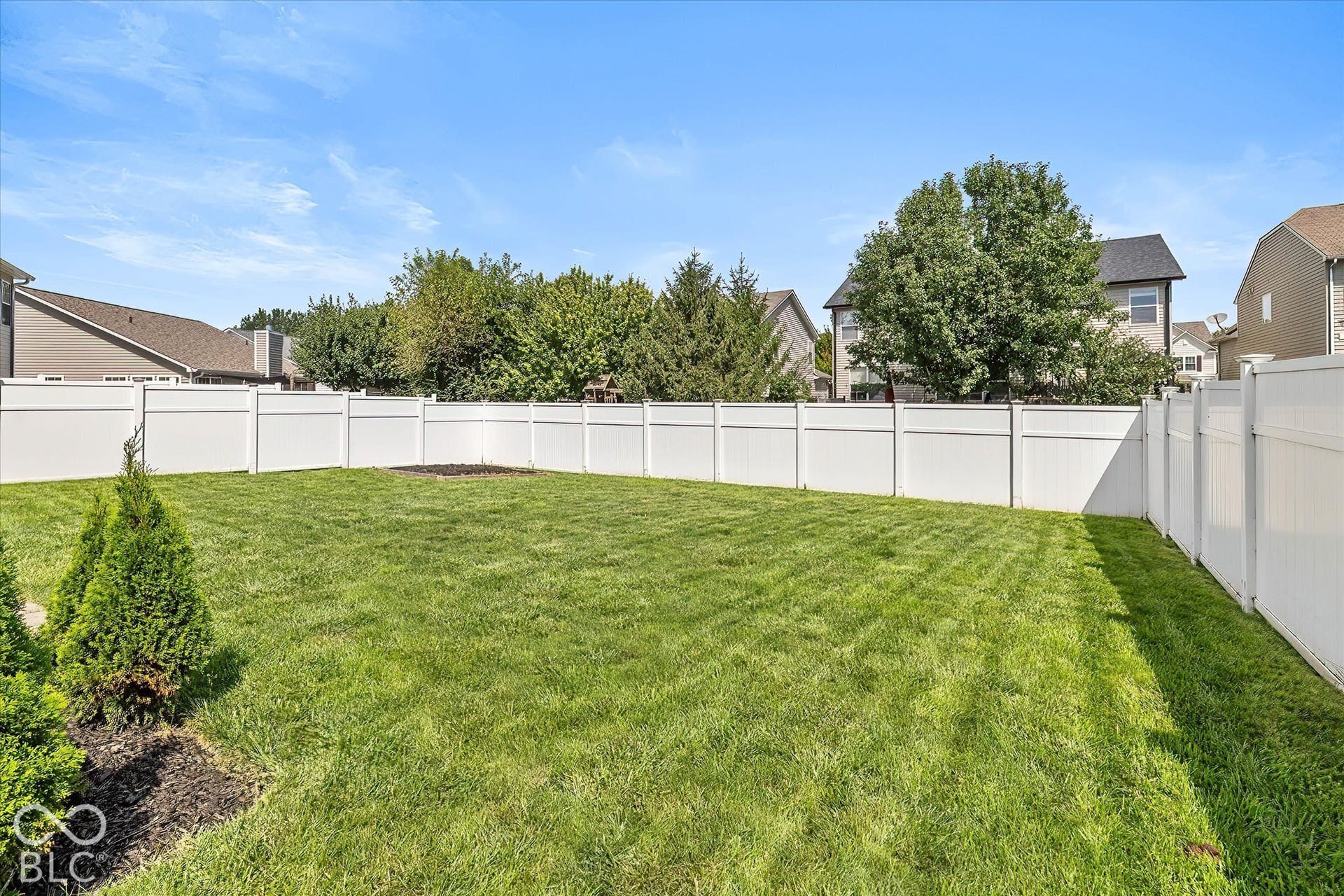 Expansive lawn area enclosed by a white privacy fence