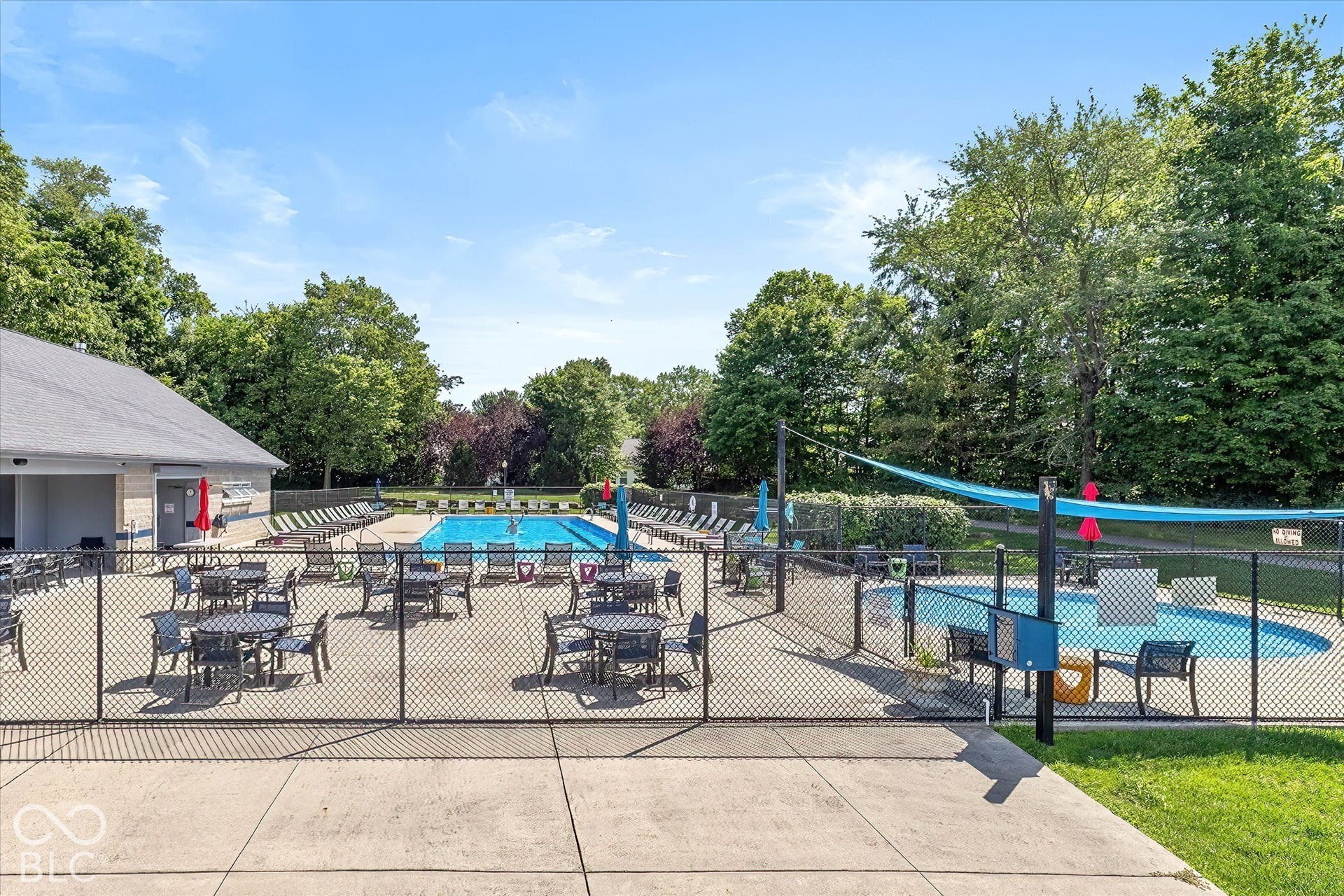 Community Pool:  Expansive outdoor concrete patio with a chain-link fence enclosure