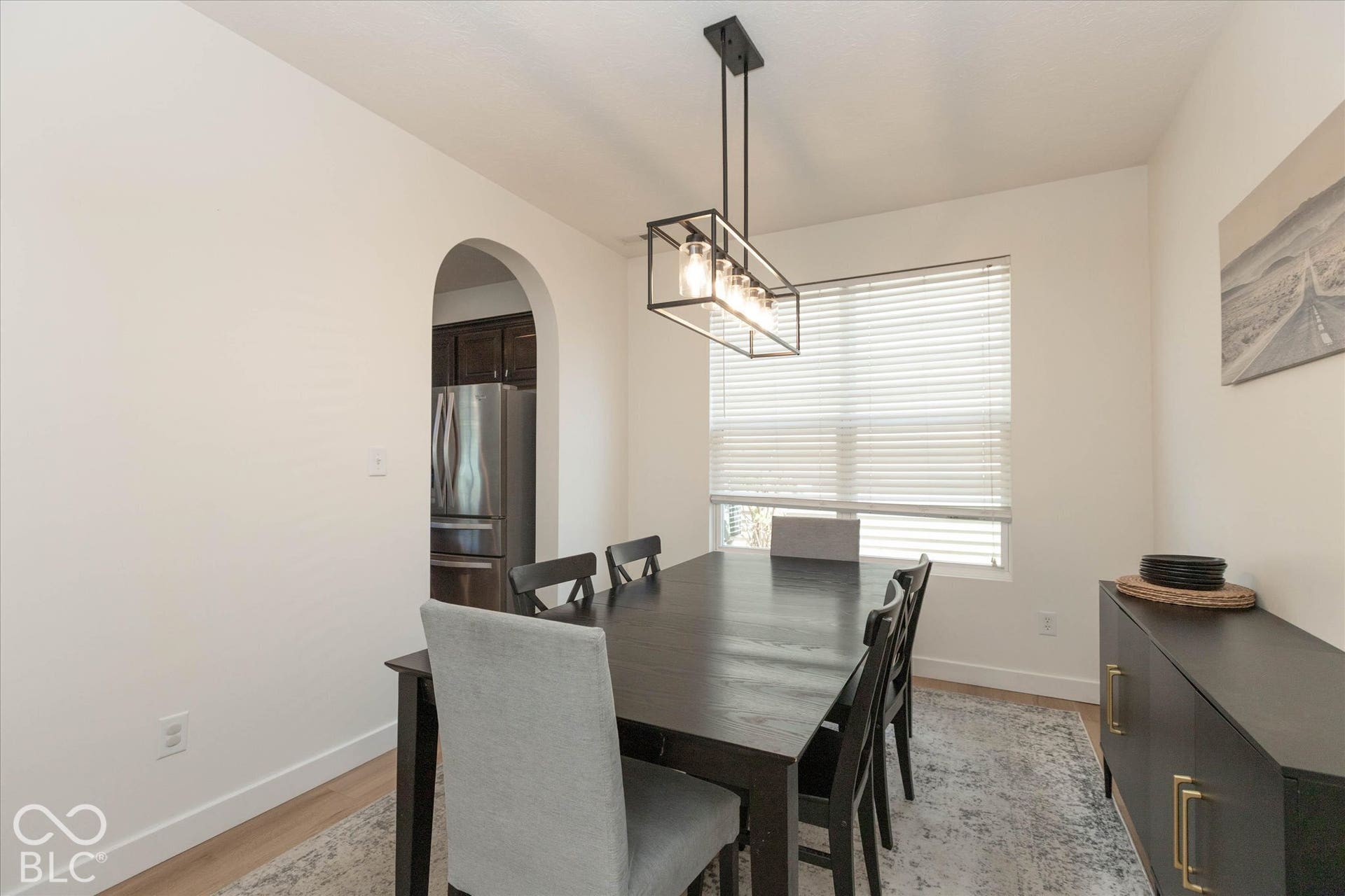 Recessed lighting with a contemporary rectangular chandelier, arched entryway, and wood-finish flooring
