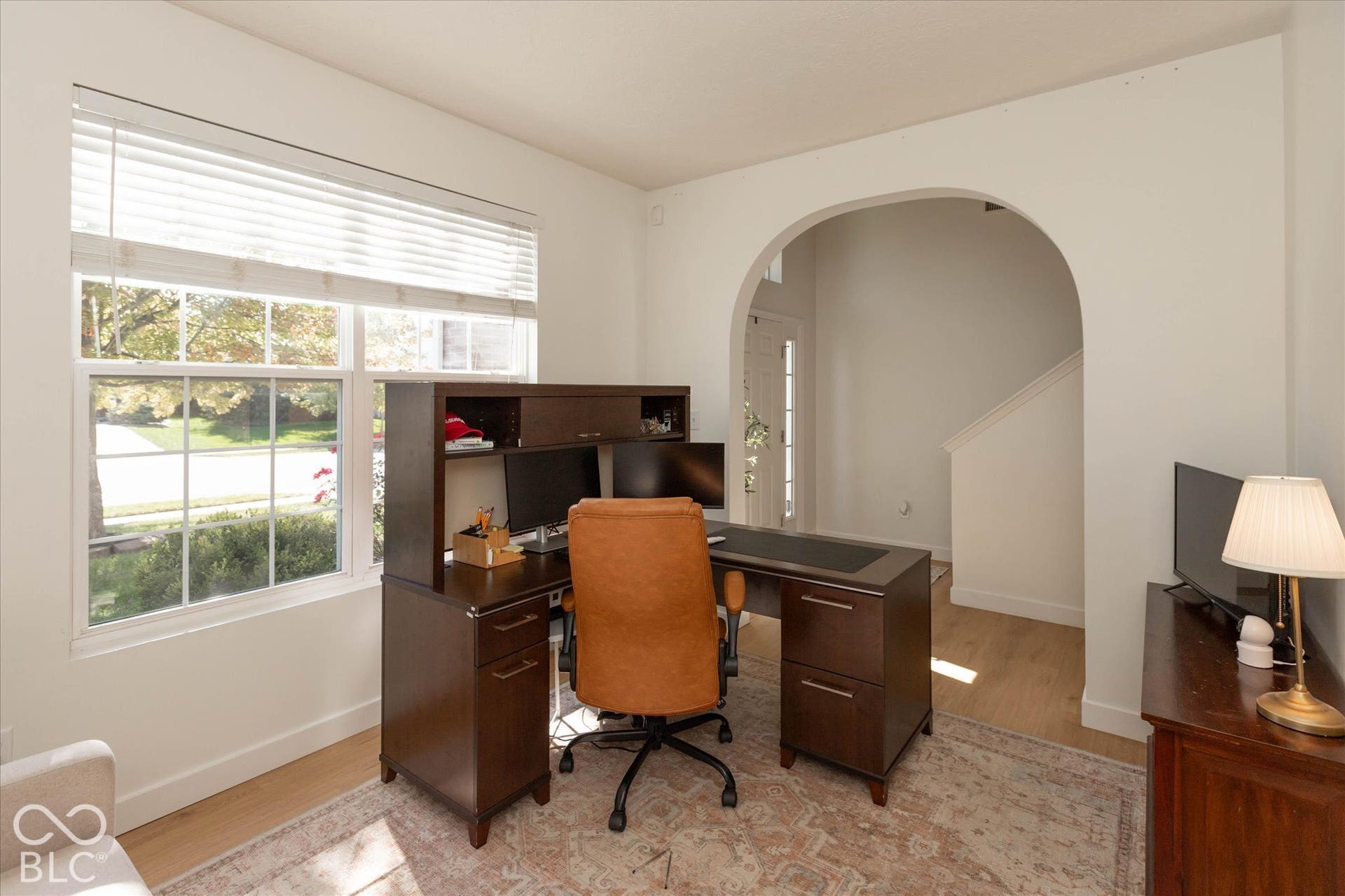 Currently being used as a home office. Spacious room featuring multiple windows, light wood-finish flooring, and an arched doorway