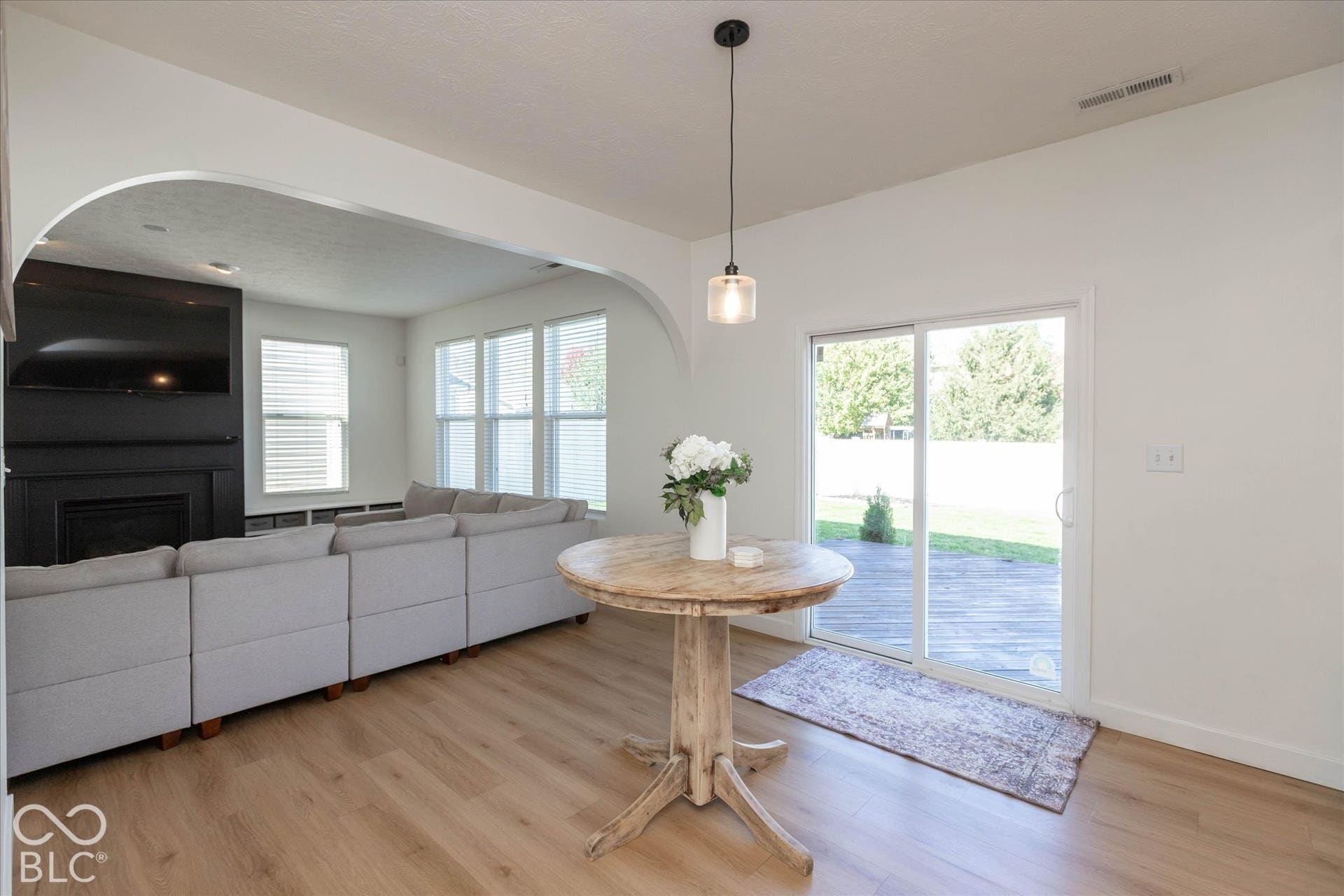 Wood-finish flooring, sliding glass door, pendant light fixture, and arched opening with a view to the family room