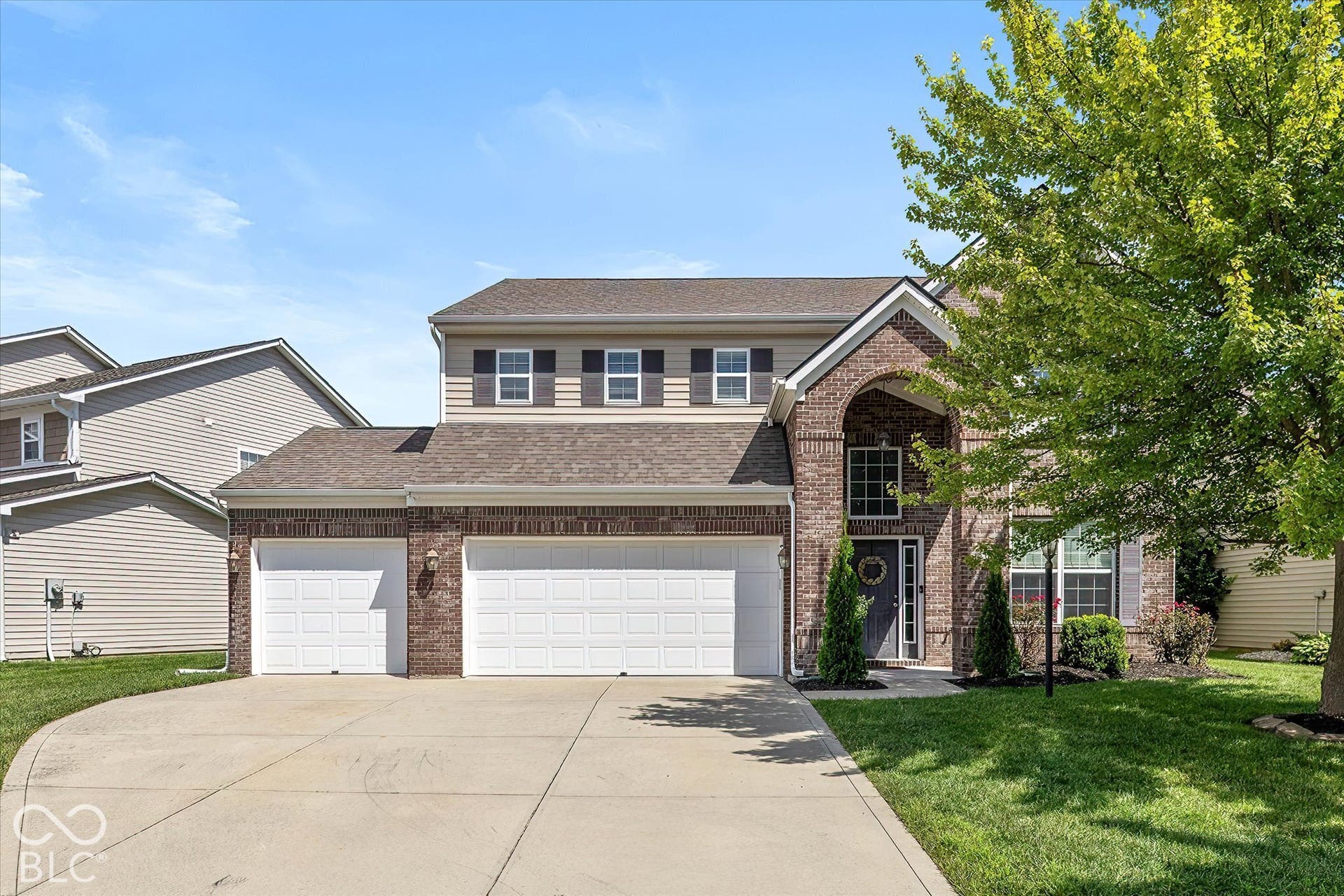 Brick and siding exterior with a multi-level roofline, arched entry, and a two-car garage