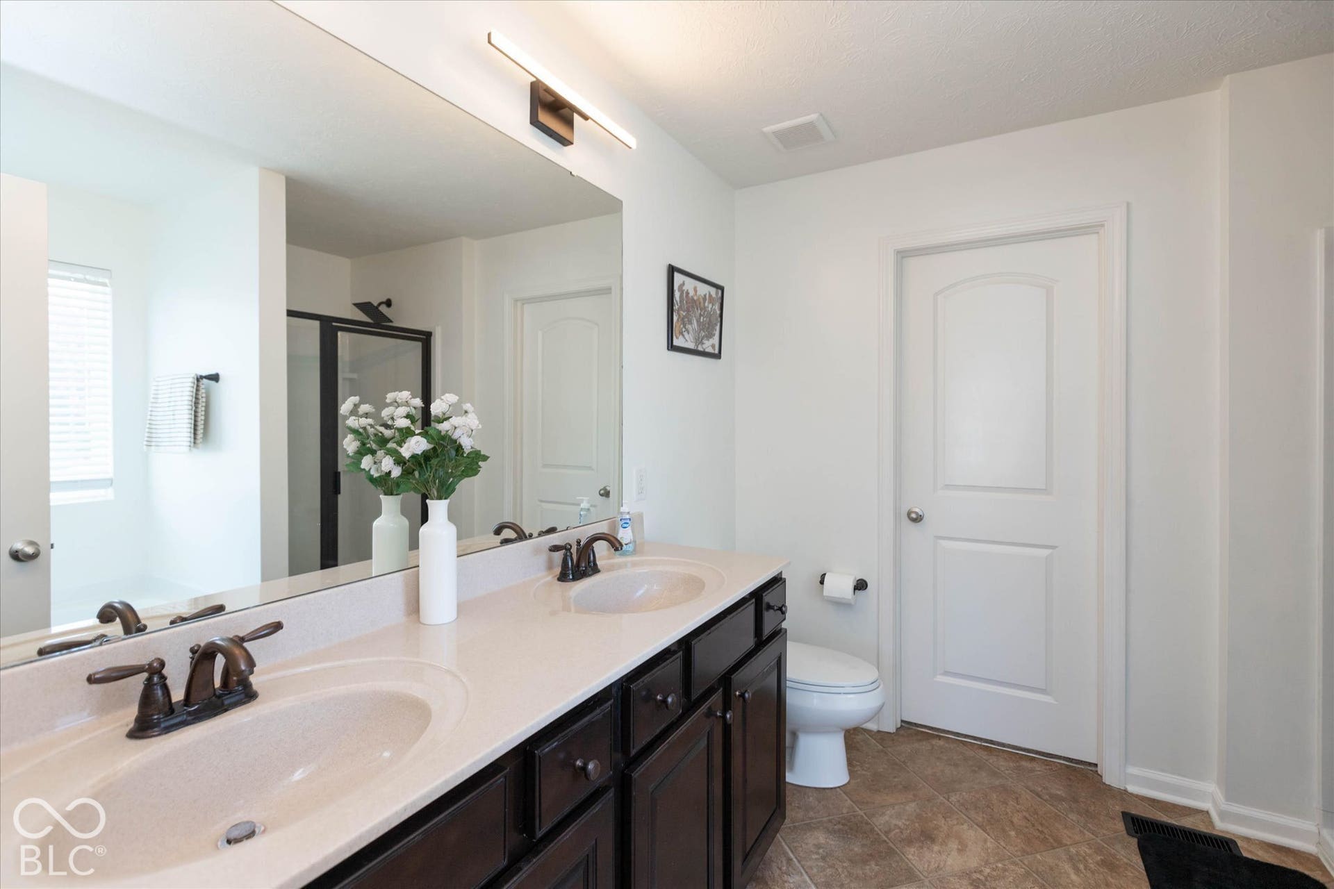 Double vanity with integrated sinks, dark wood-finish cabinetry, and oil-rubbed bronze fixtures