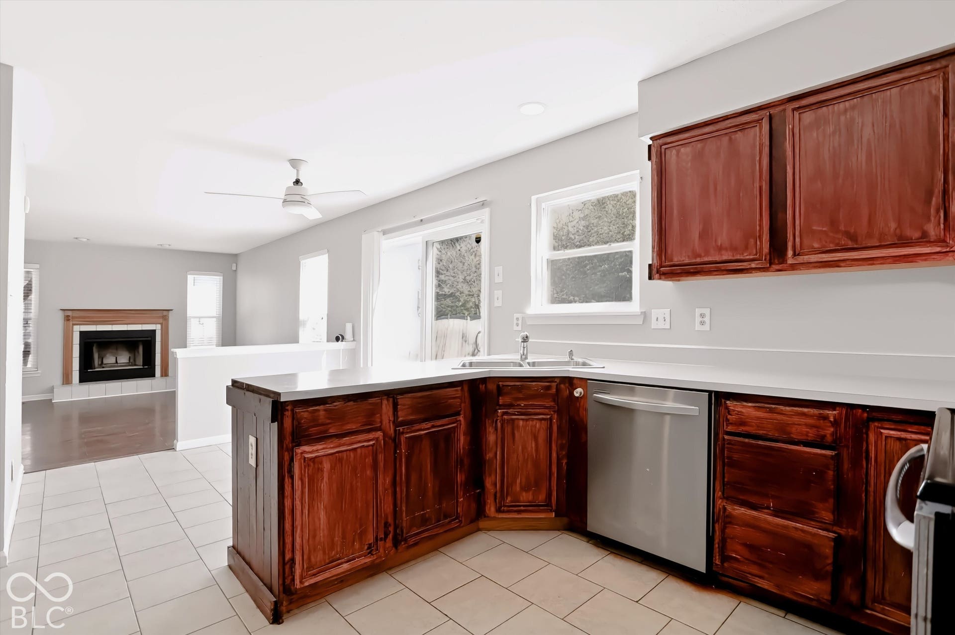 Kitchen featuring wood cabinetry, light-toned countertops, and stainless steel dishwasher
