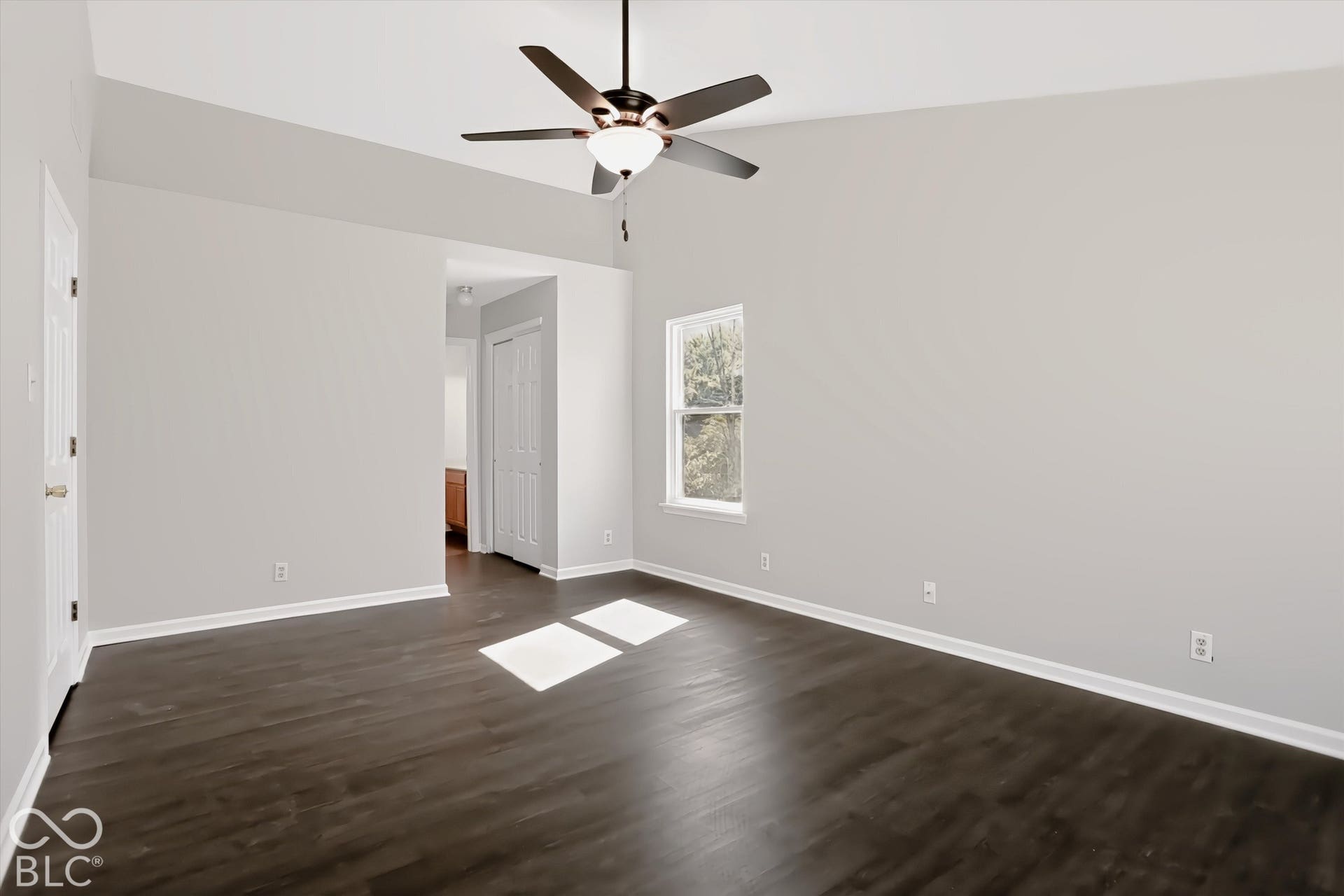 Vaulted ceiling with a ceiling fan, dark wood-finish flooring, and white trim