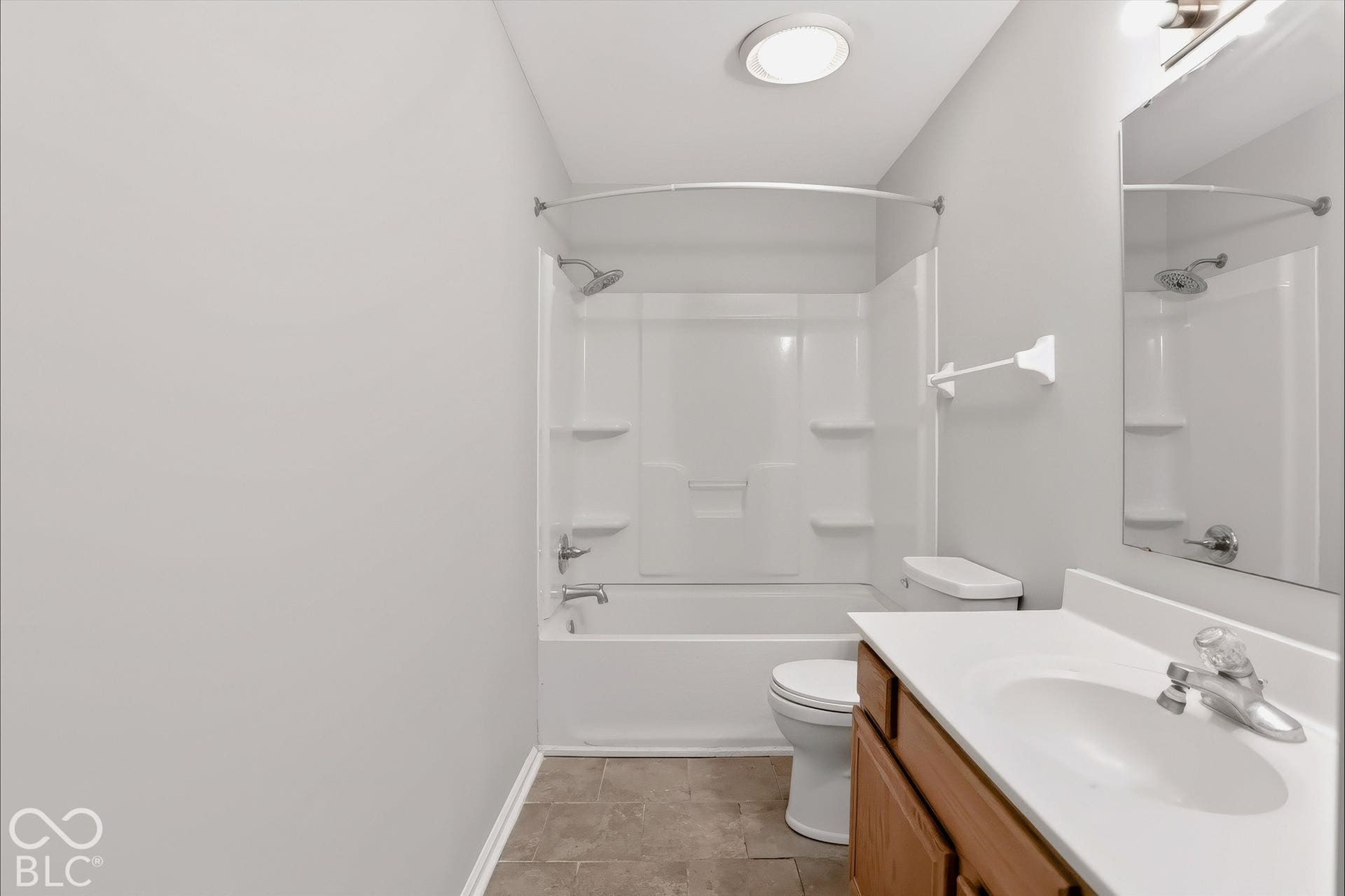 Virtually Altered - Bathroom featuring a white vanity with a single sink, an integrated mirror, and a shower-over-tub combination with a curved shower rod