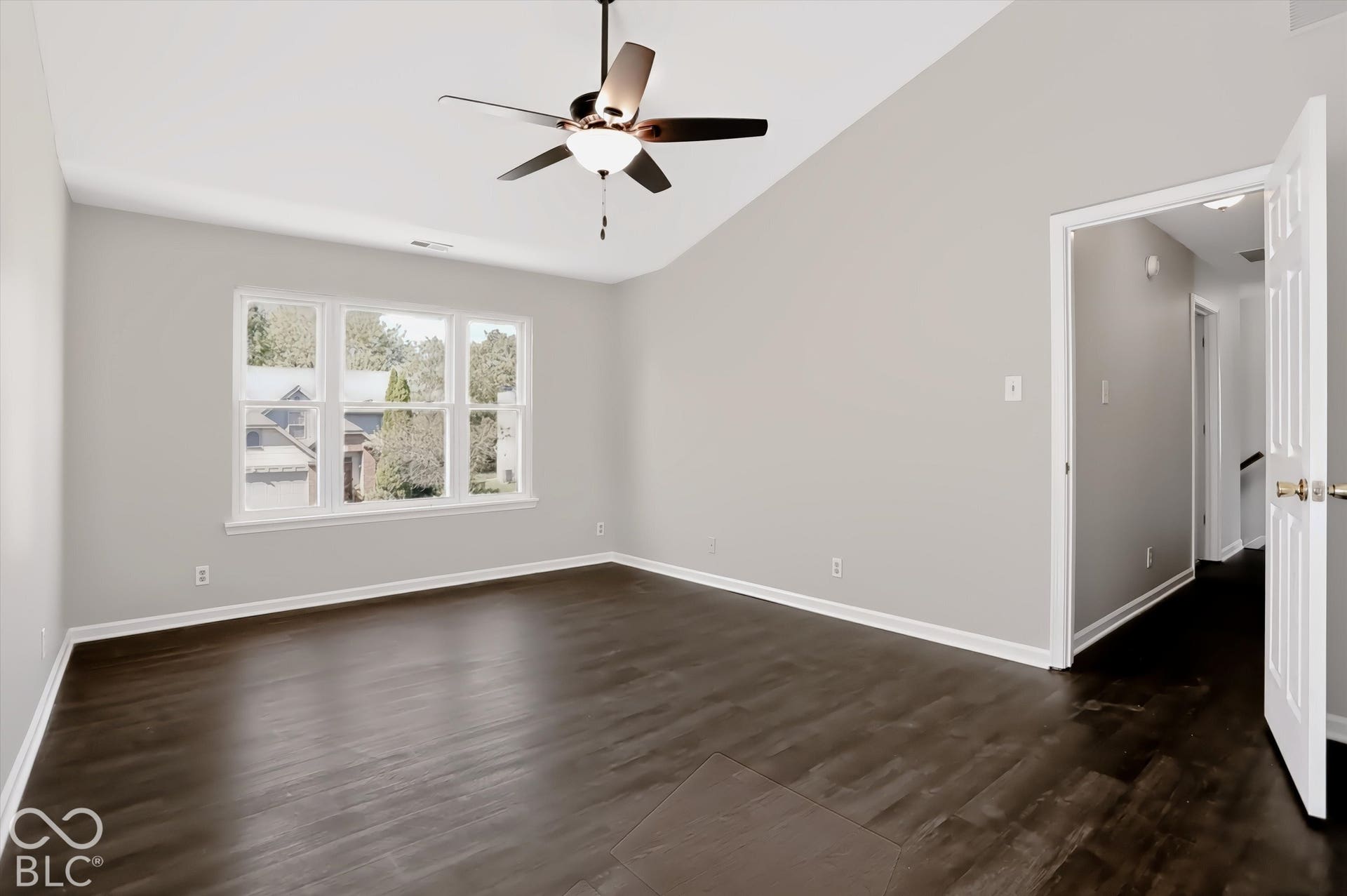Vaulted ceiling with a ceiling fan, dark wood-finish flooring, and light-toned wall paint